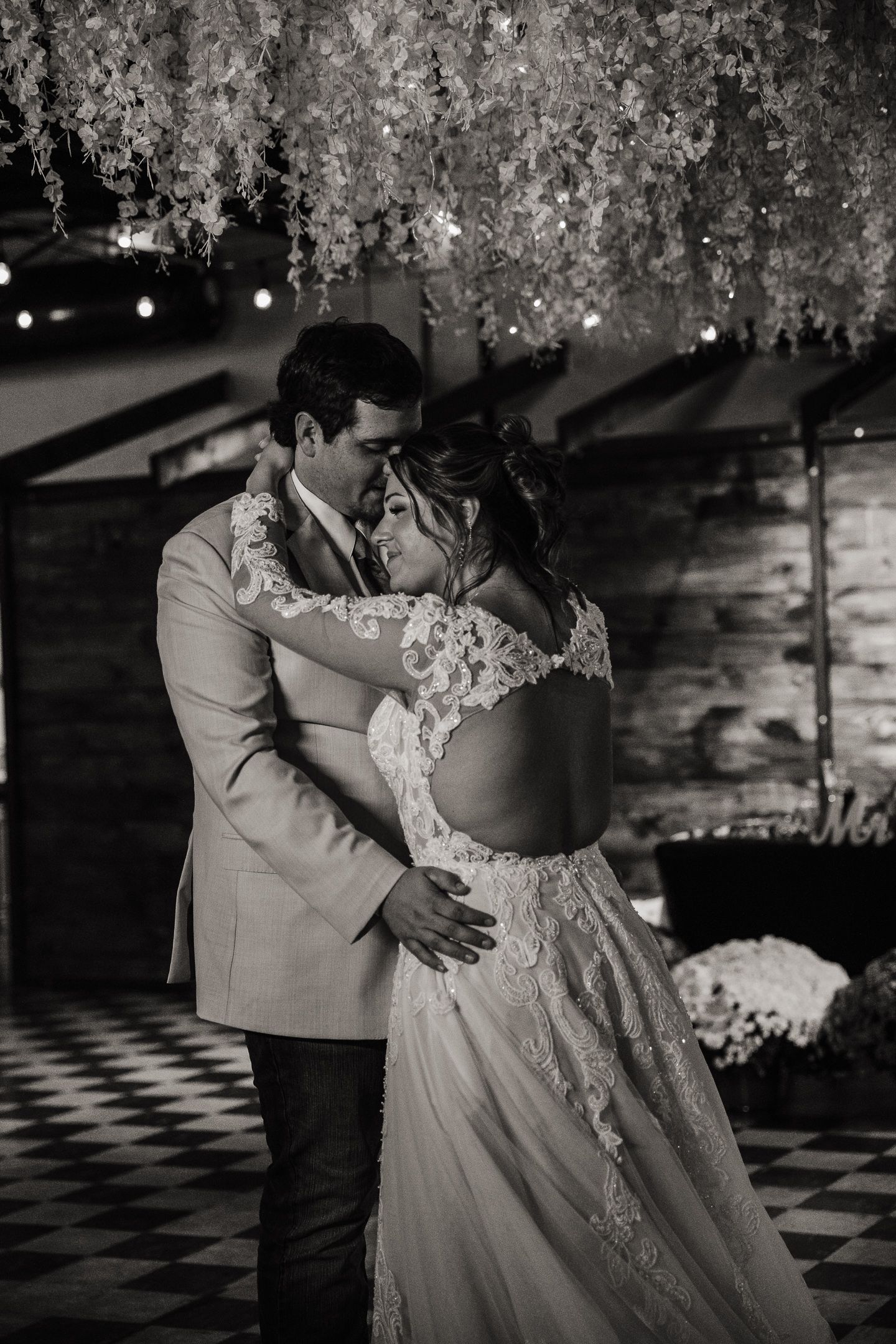 Romantic black and white wedding portrait under hanging floral installations.