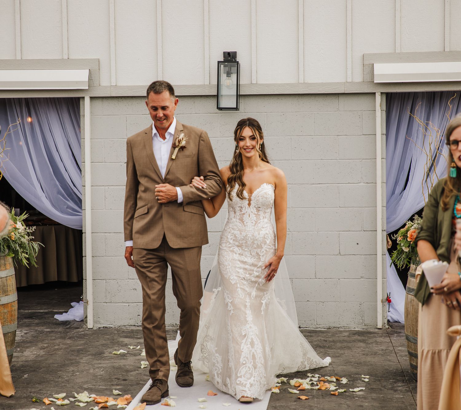 Wedding couple poses for photos in front of white building with rustic decor.