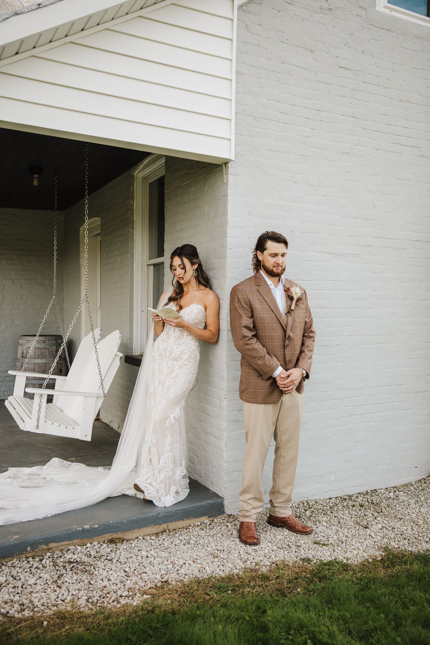 Couple poses playfully by white house exterior with porch swings.