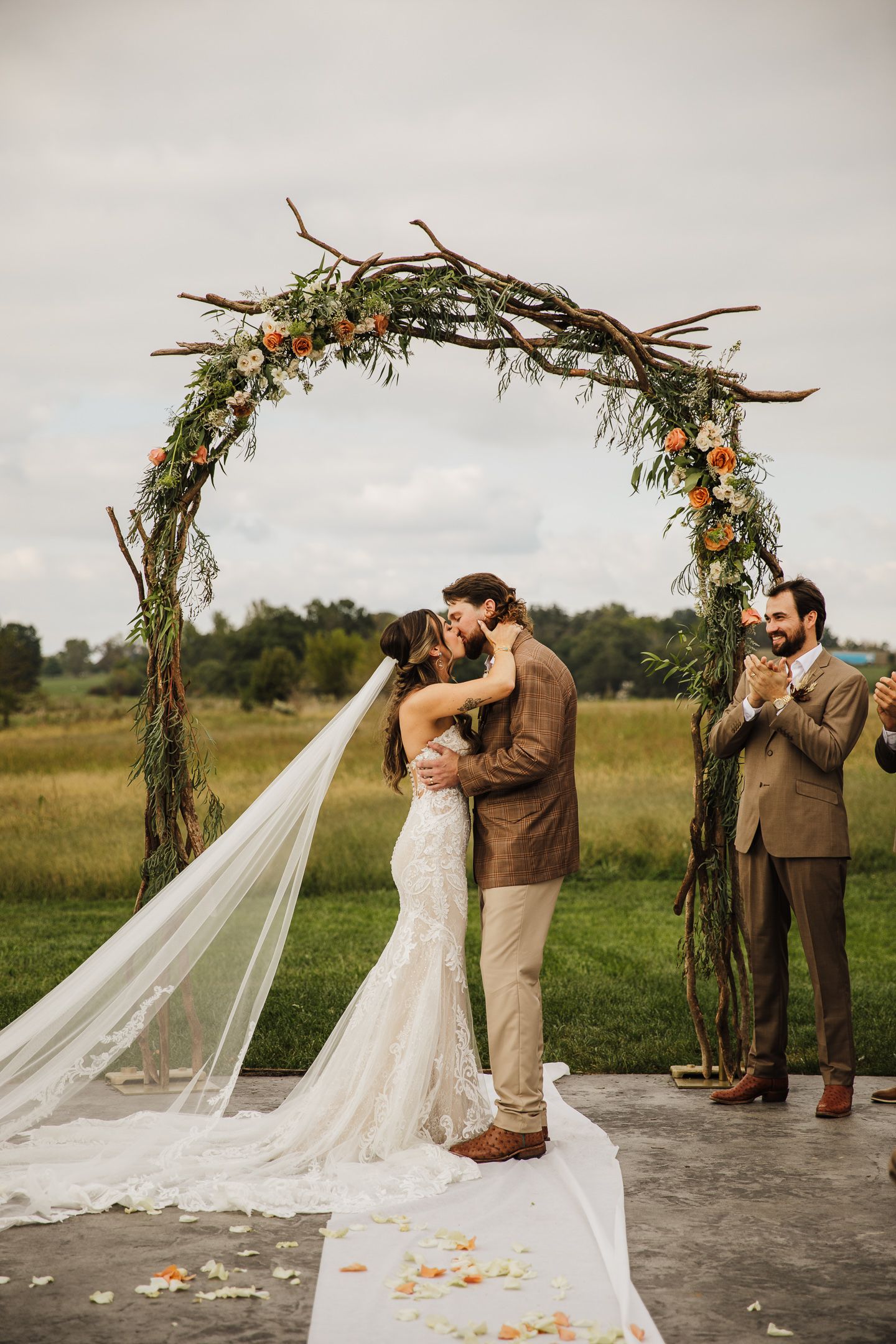 Wedding couple shares first look moment under rustic floral arch in outdoor setting.