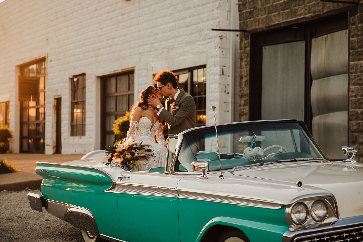 A couple poses with a vintage turquoise and white car during their wedding photoshoot.