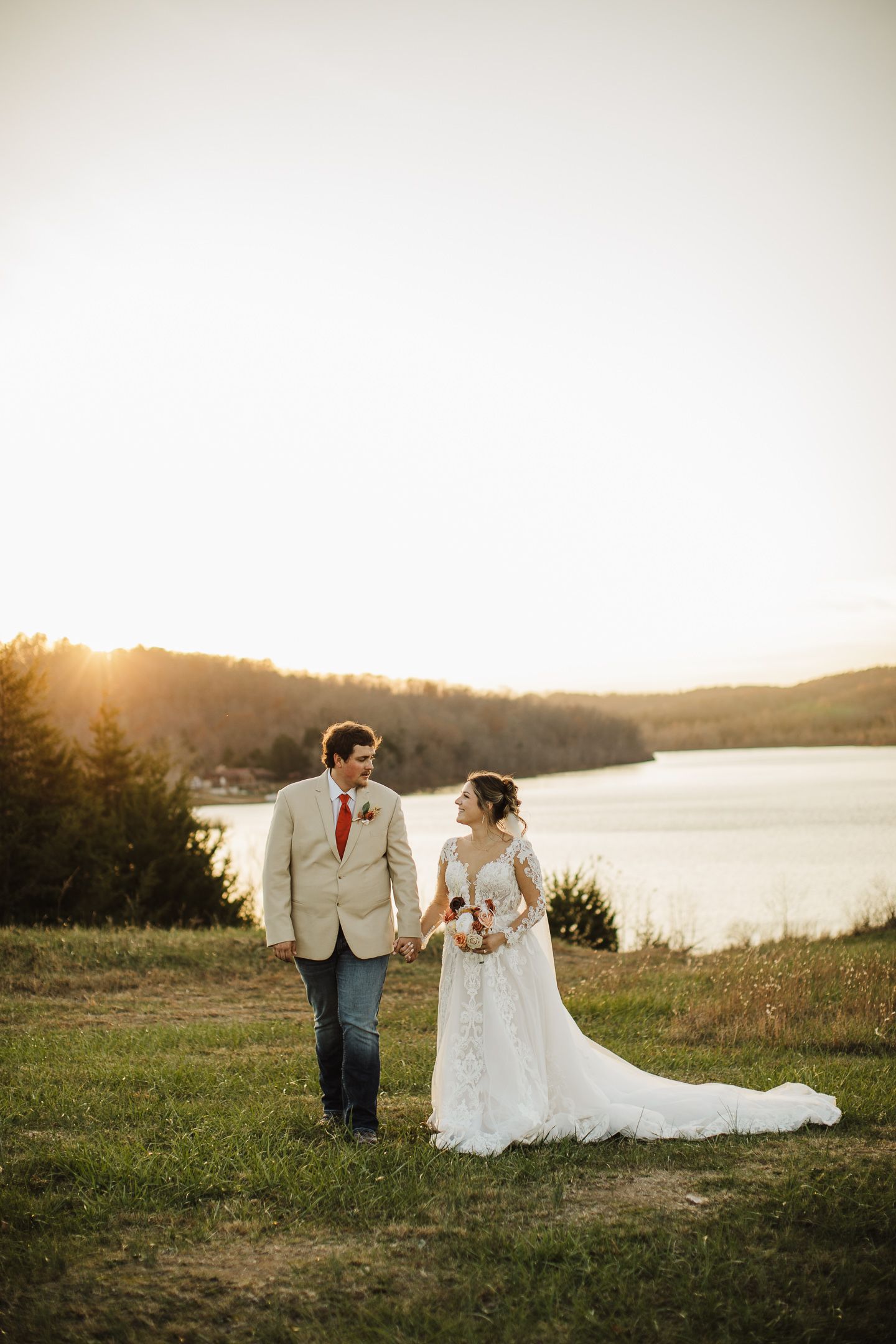 A lakeside wedding photo session at sunset with rolling hills and water in the background.
