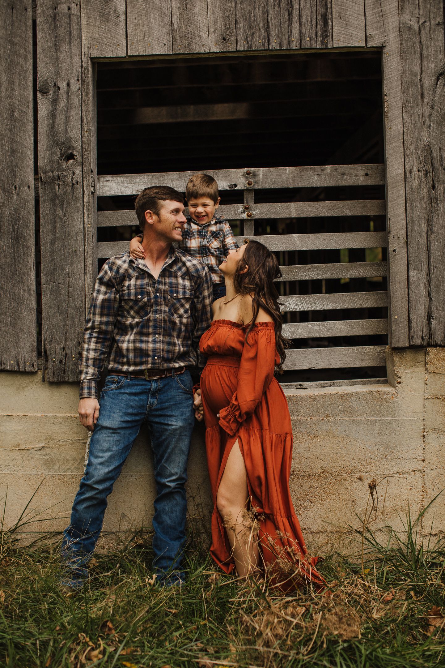 A rustic family photo shoot in front of a weathered wooden barn door.