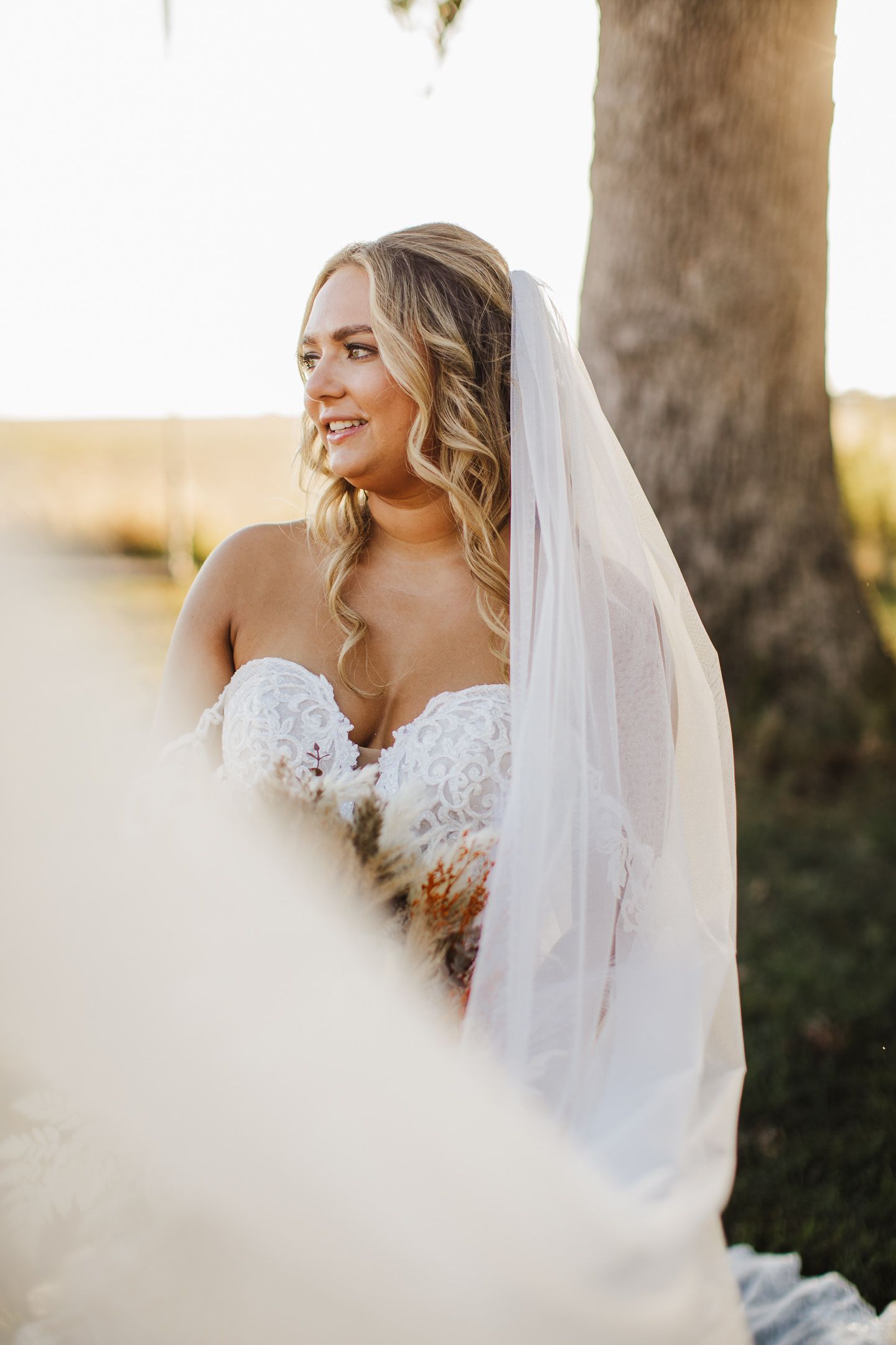 Ethereal bridal portrait with flowing veil captured in golden sunlight.
