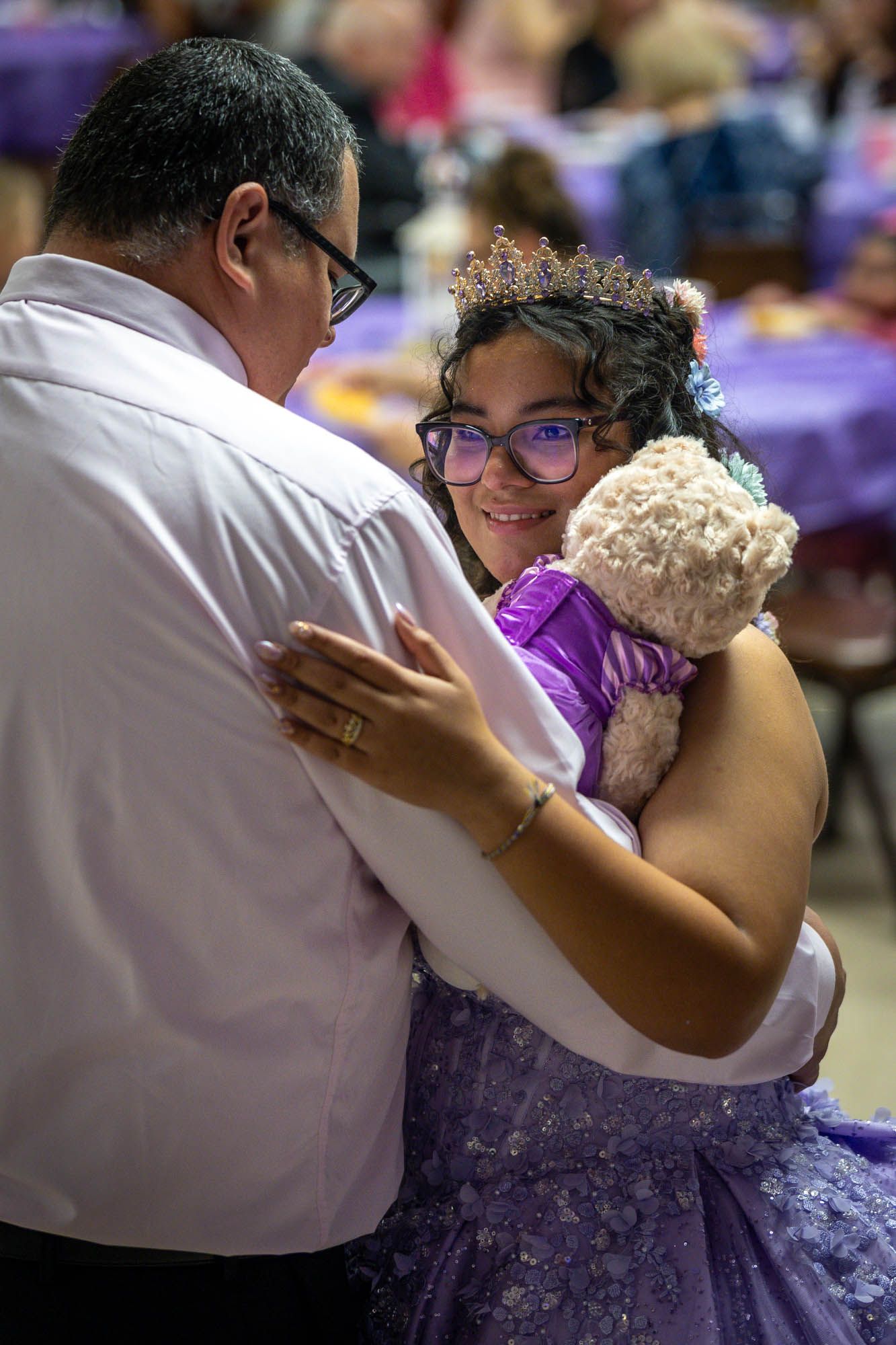 Father and daughter sharing a tender dance at a purple-themed Quinceañera celebration.
