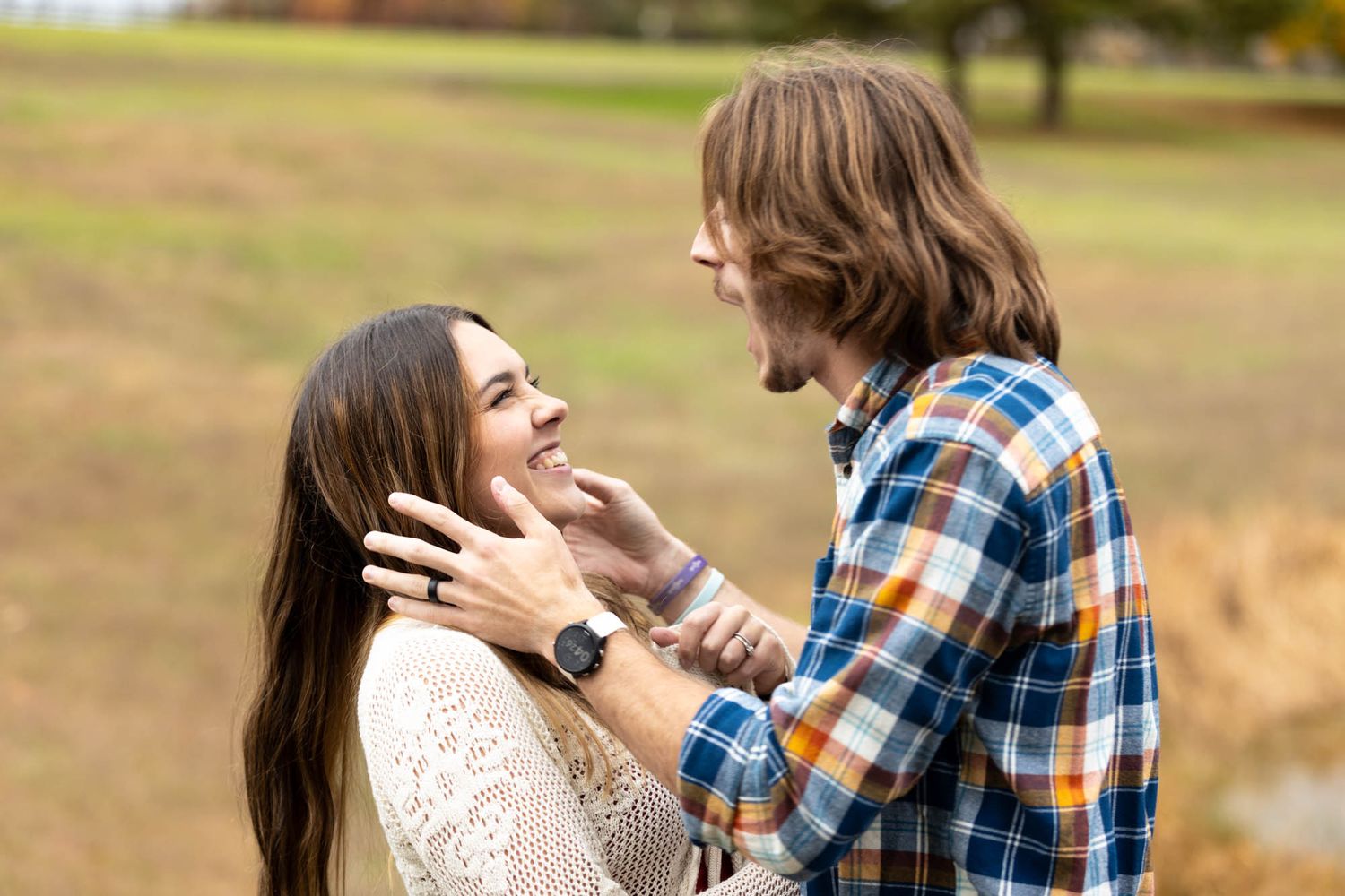 Couple shares a tender moment as man gently touches womans face in autumn park setting.
