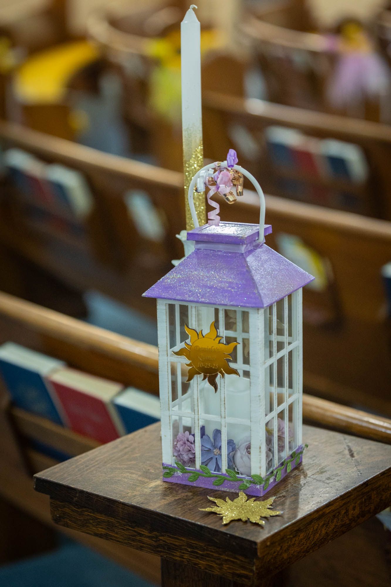 Purple and white decorative lantern with candle and sun ornament on wooden church pew.