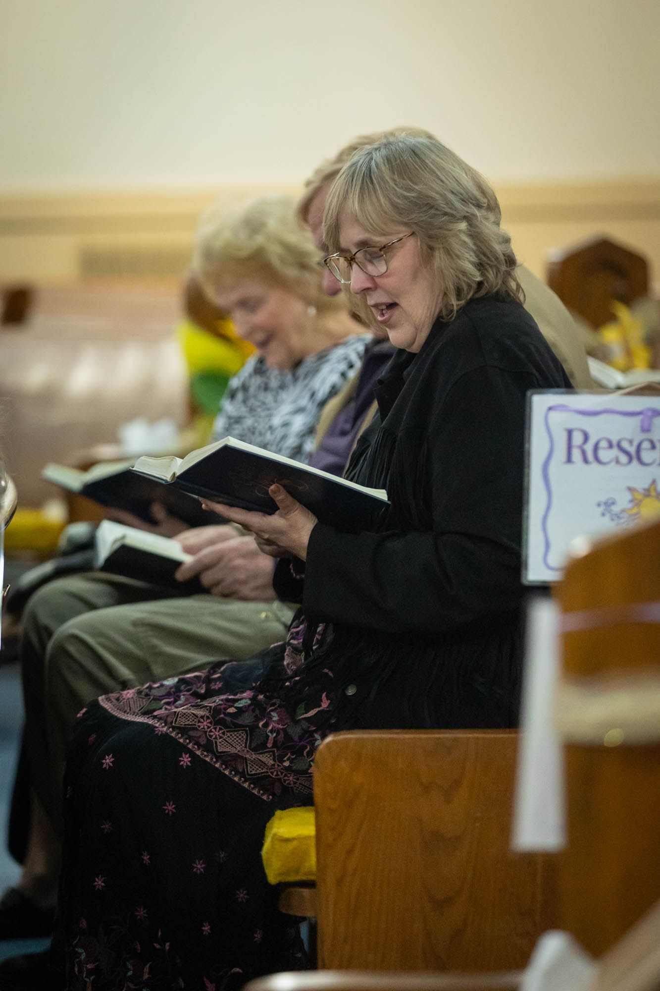 Woman reading from a hymnal book during a Quinceañera church ceremony service.