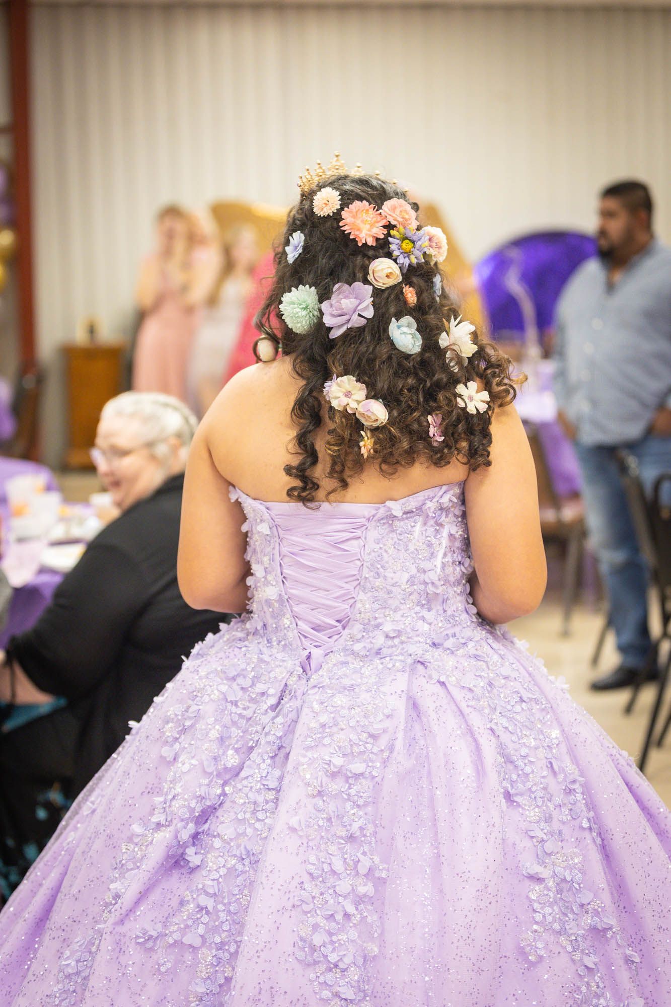 Quinceañera girl in lavender ballgown with colorful flowers in curly hair.