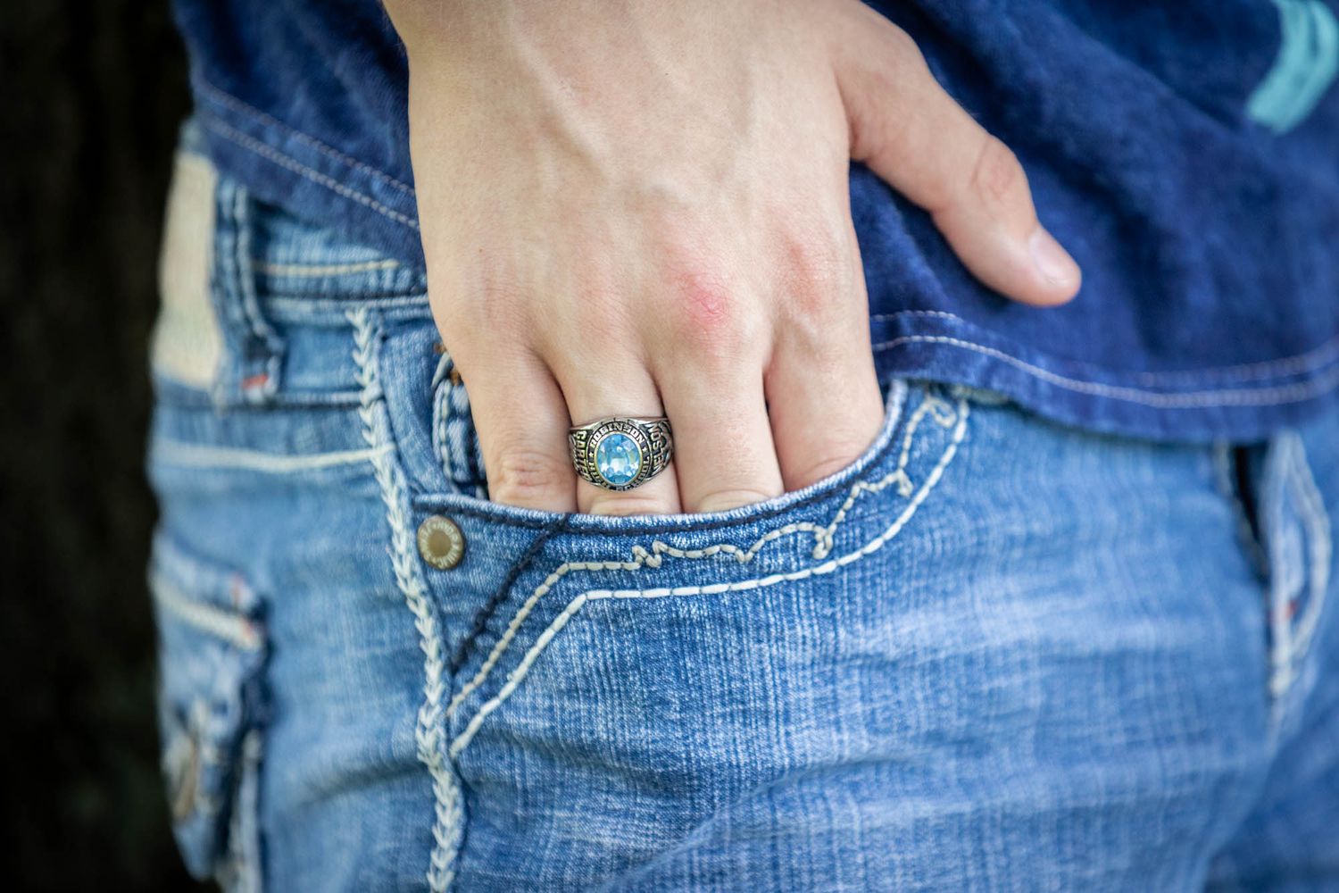 Hand with silver turquoise ring tucked into blue denim jeans pocket, showcasing stylish western jewelry.
