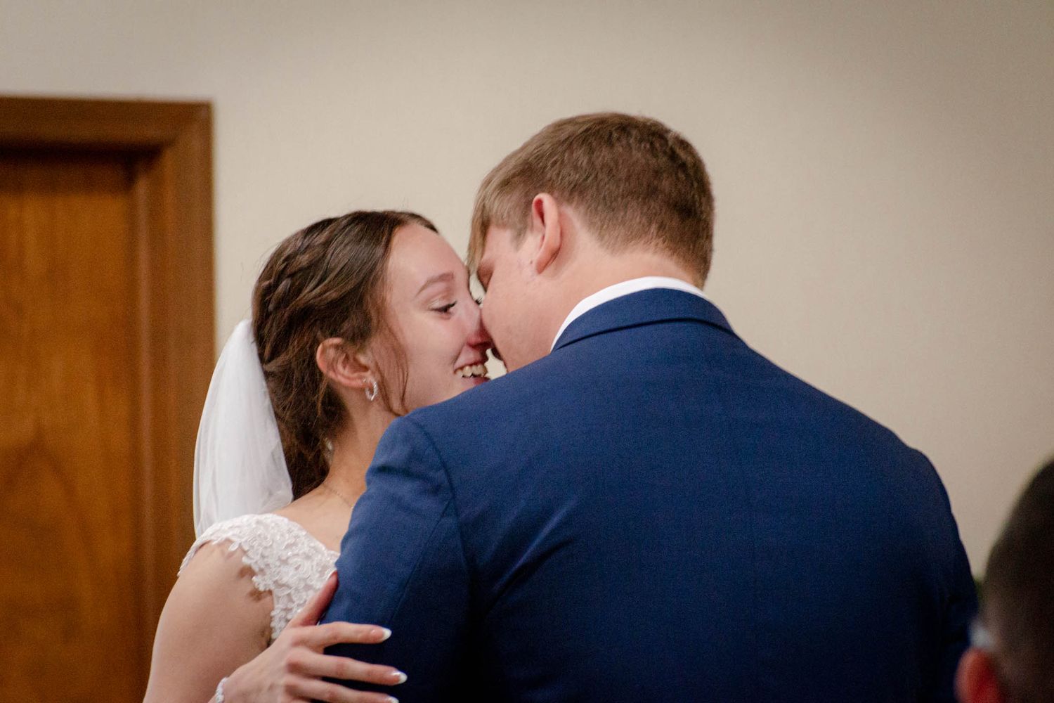 Bride and groom sharing their first kiss during an intimate indoor wedding ceremony.