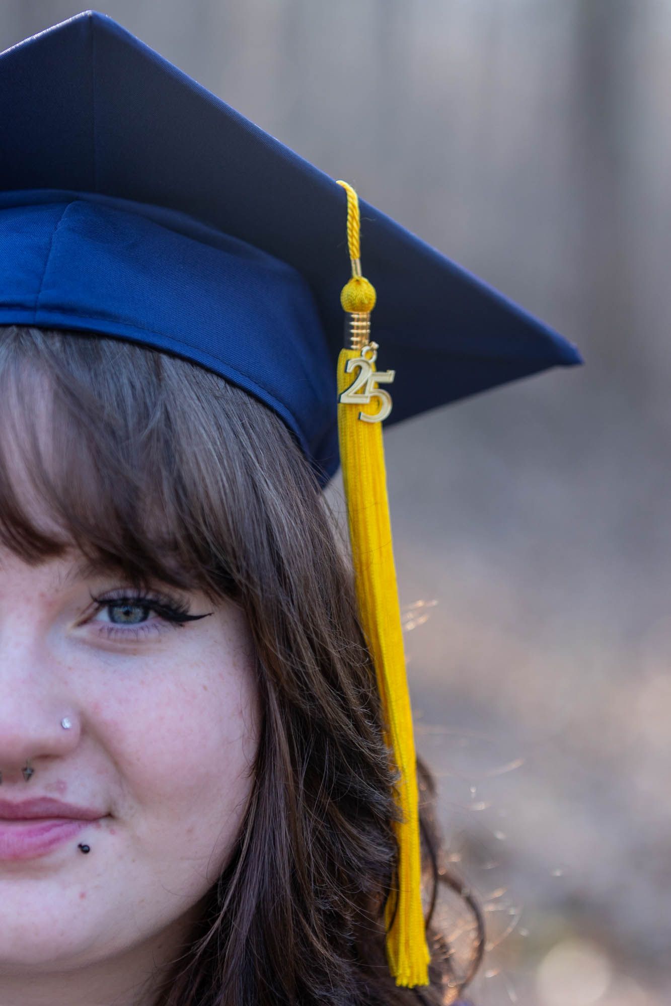 Close-up of a graduate wearing a blue cap with a gold 2025 tassel for a graduation portrait.