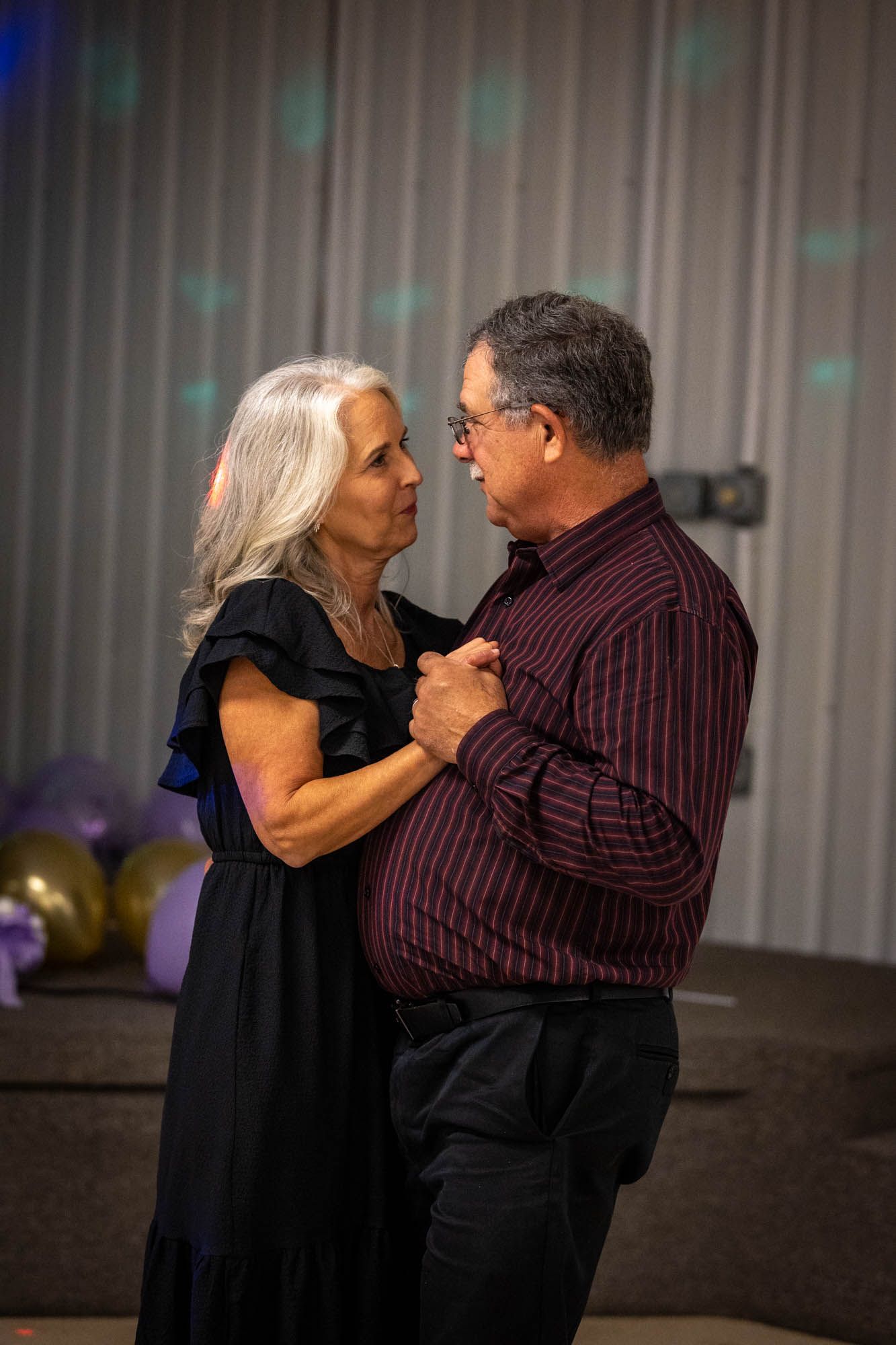Elegant older couple sharing a romantic slow dance at a Quinceañera celebration event.