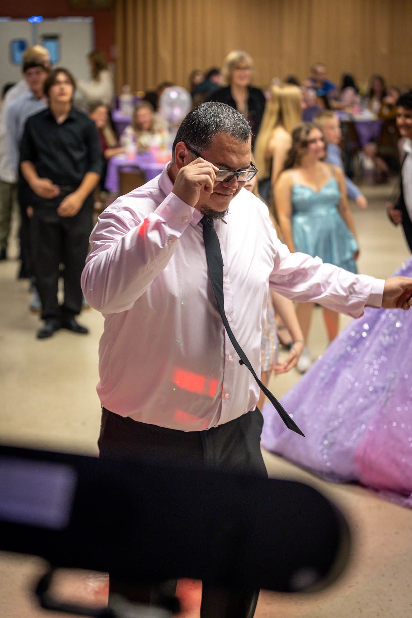 Man in pink shirt dancing enthusiastically at quinceañera celebration.