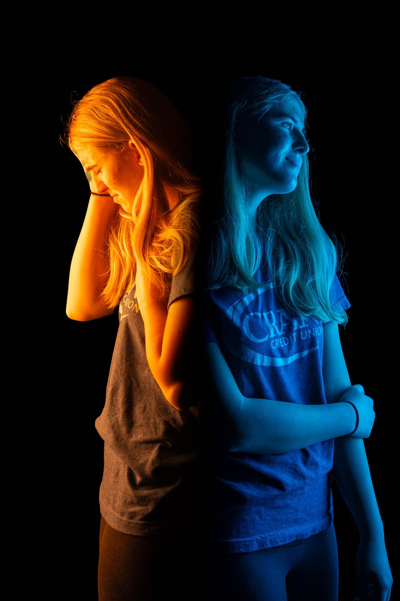 Blonde woman back-to-back portrait in orange and blue lighting depicting contrasting emotional states of sadness and calm.