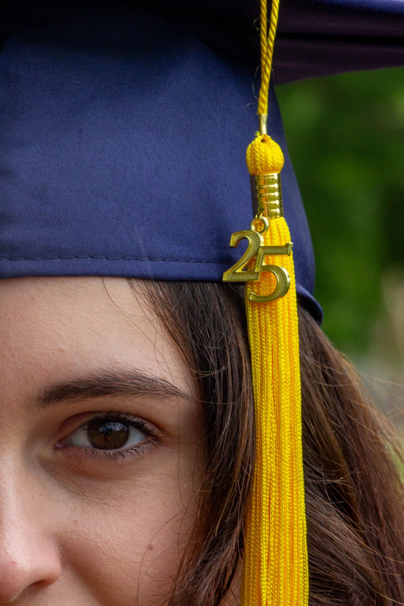 Close-up of a young woman wearing a navy blue graduation cap with a gold tassel and 2025 charm.