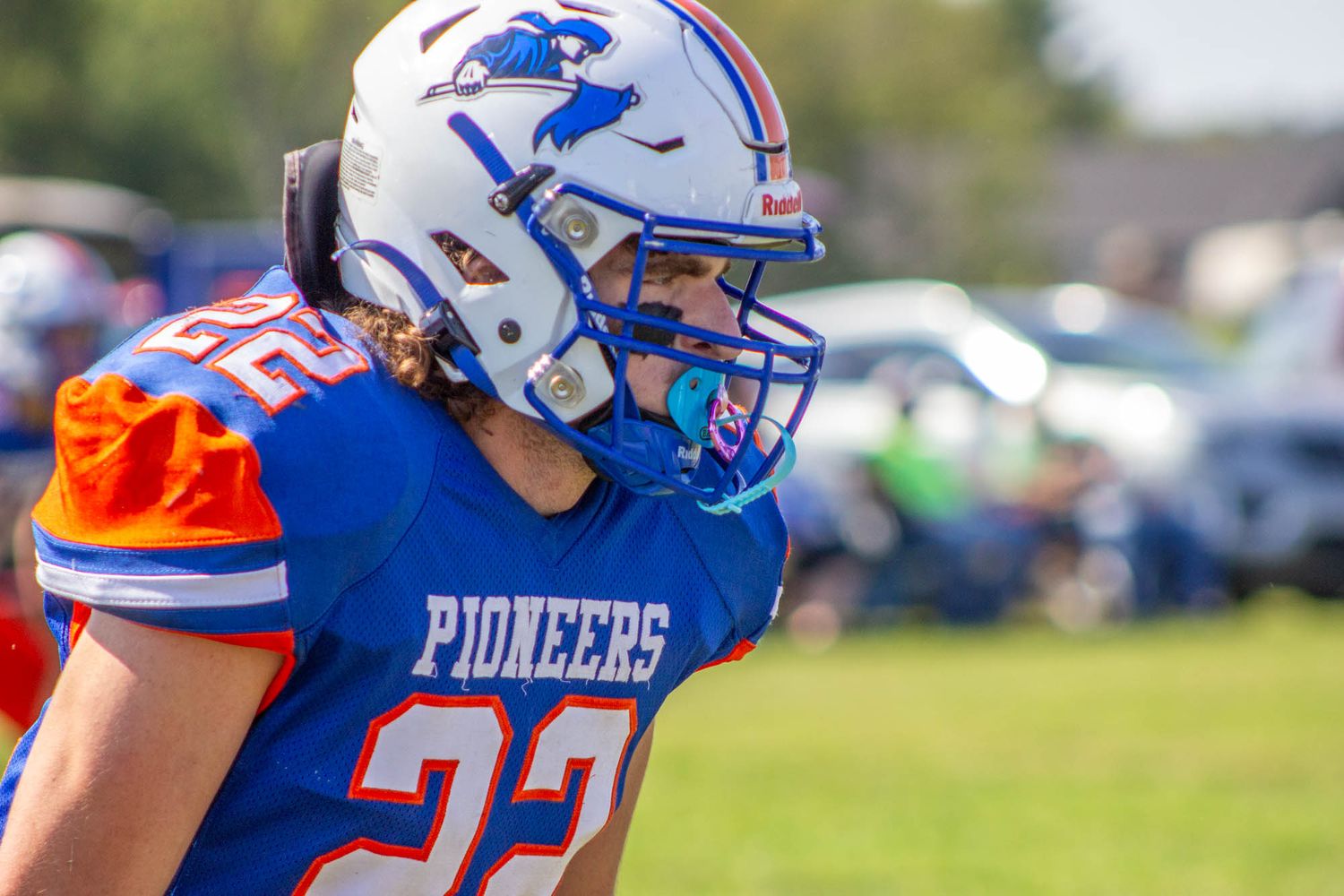 Close-up of Pioneers youth football player #22 wearing a white and blue helmet on the field.