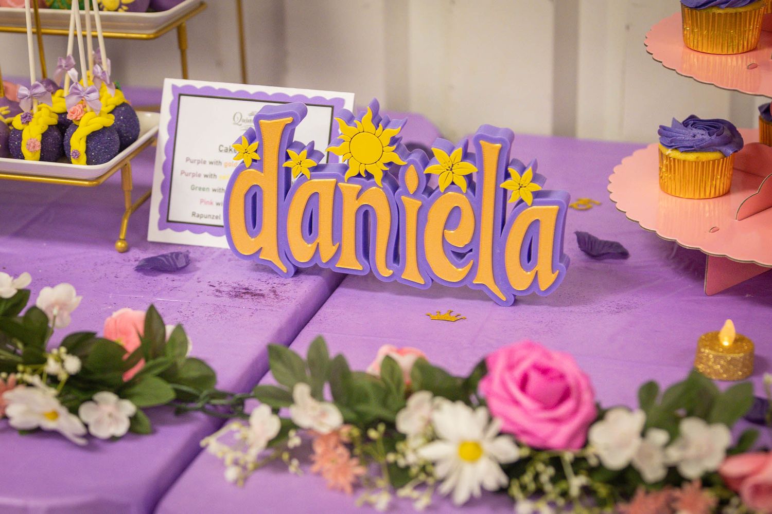 Decorative Daniela name sign on purple table at quinceañera celebration.
