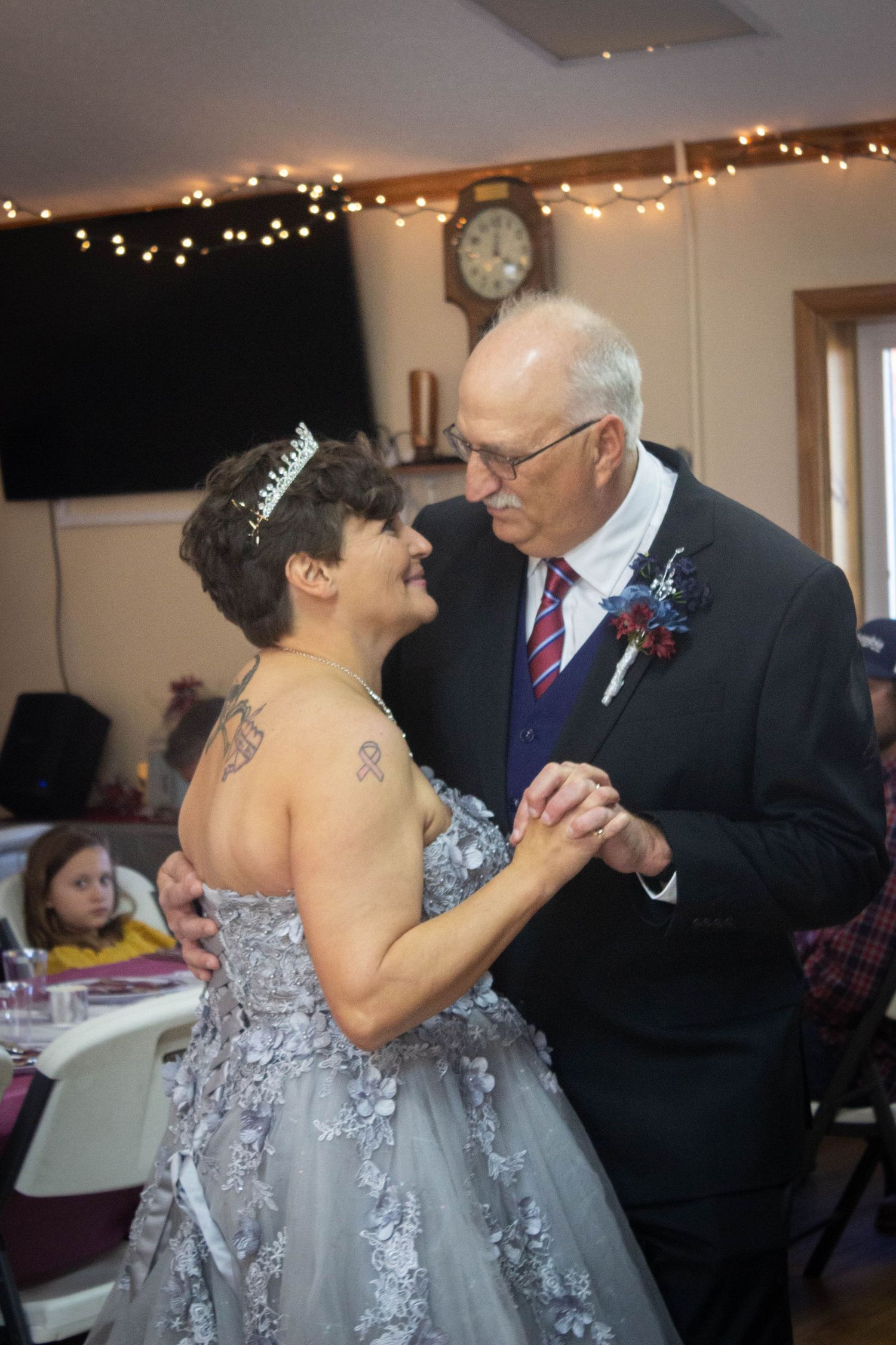 Bride in silver gown and tiara sharing first dance with groom at reception.