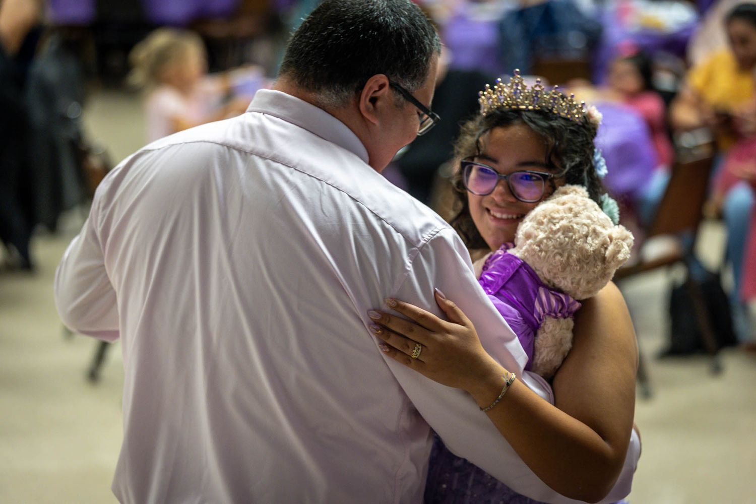 Man and girl in purple dress share a tender dance embrace at a quinceañera celebration.