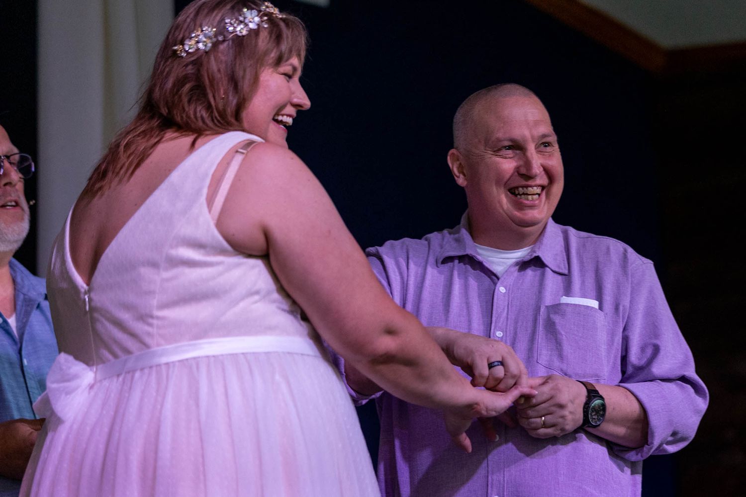 Bride and groom laughing joyfully while exchanging rings at their wedding ceremony.
