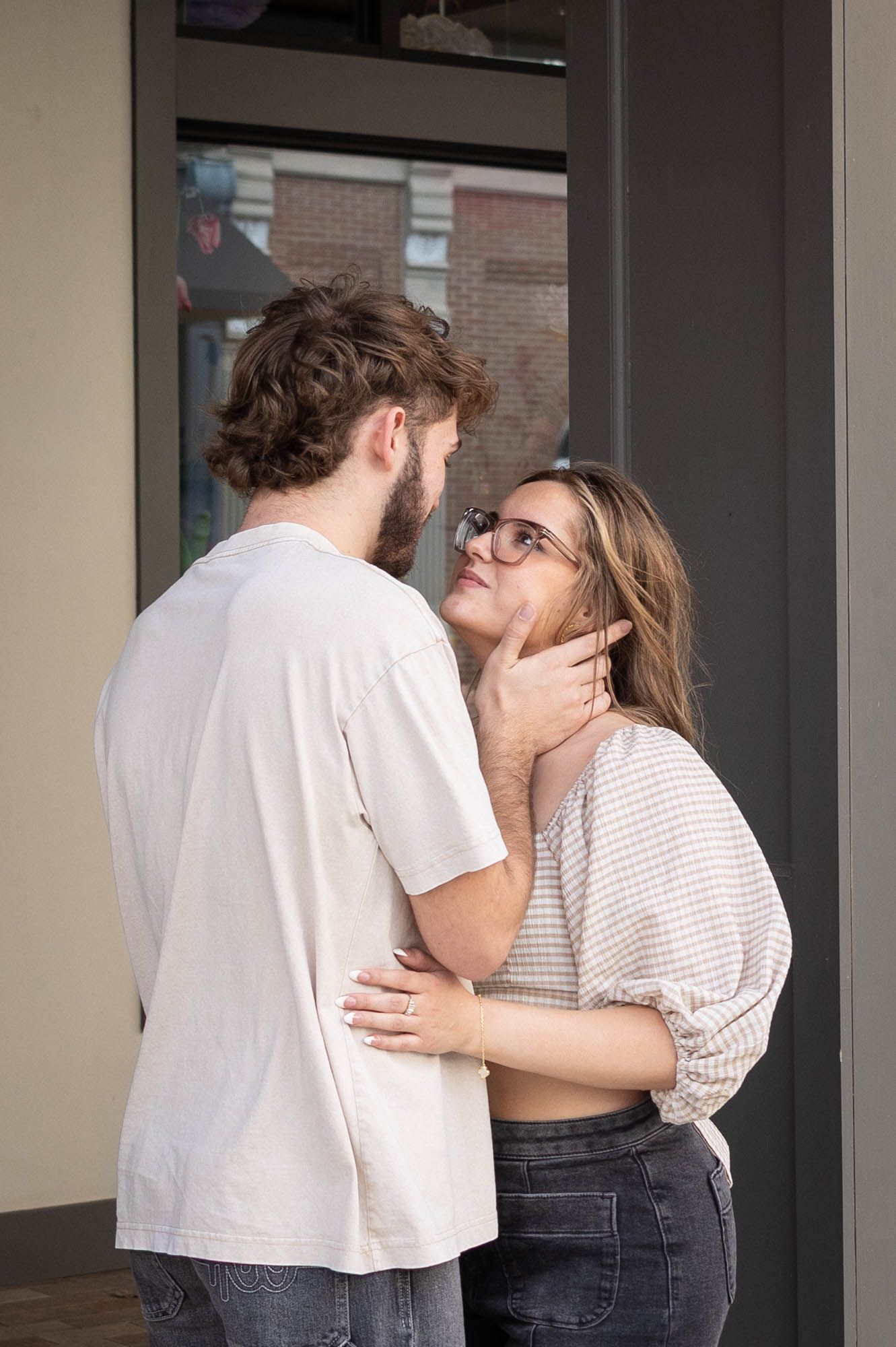 A couple shares a tender moment, with a man gently holding a woman's chin as she gazes up at him lovingly.