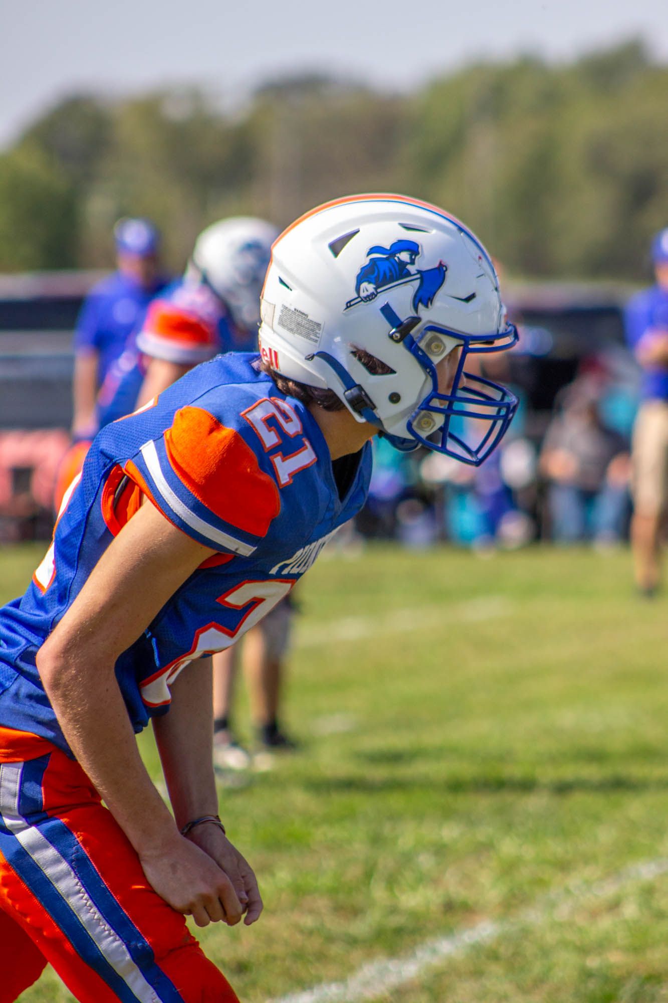 Close-up side profile of a high school football player wearing a white helmet with blue logo during a game.