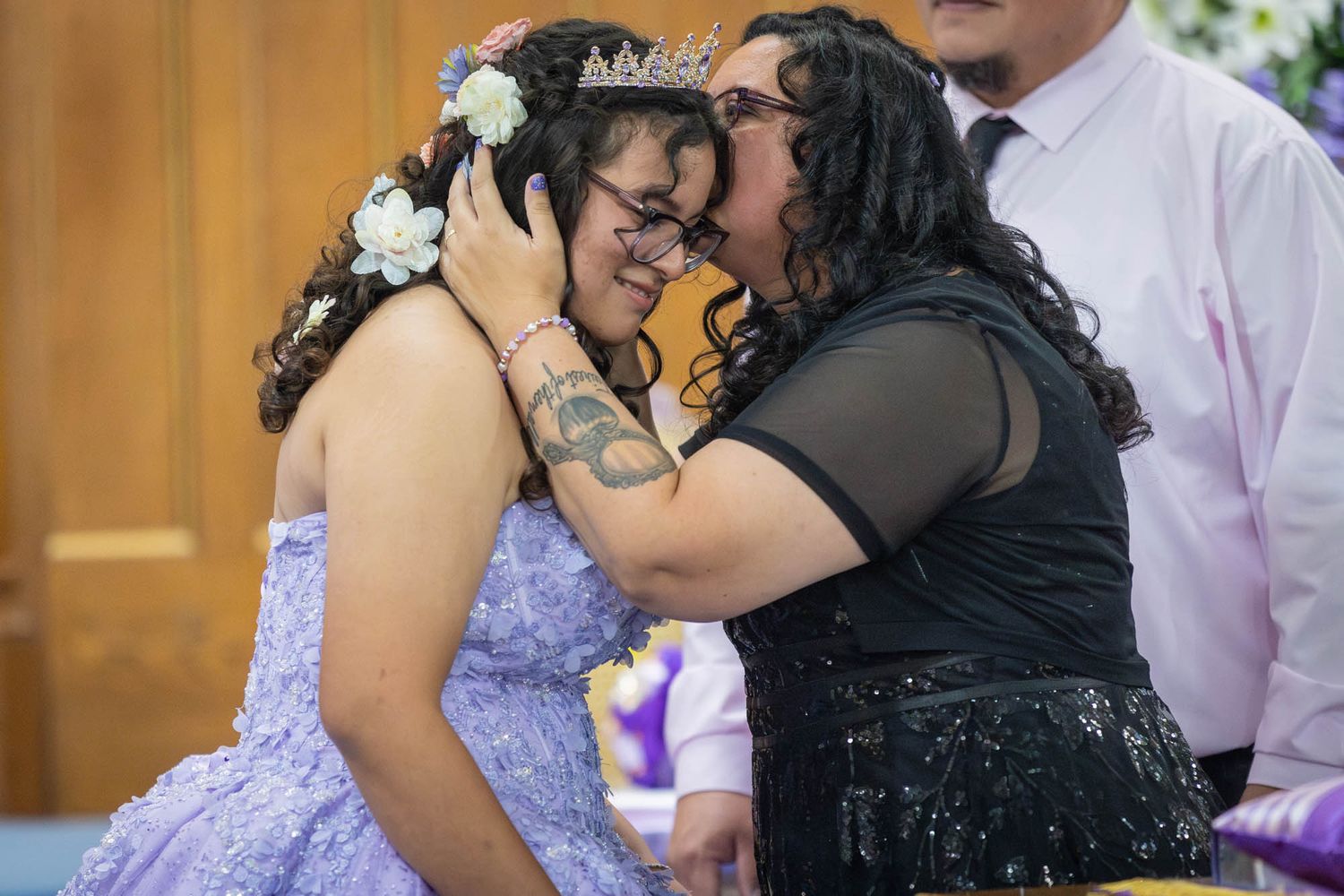 Emotional mother placing a tiara on her daughters head during a quinceañera celebration in a church.