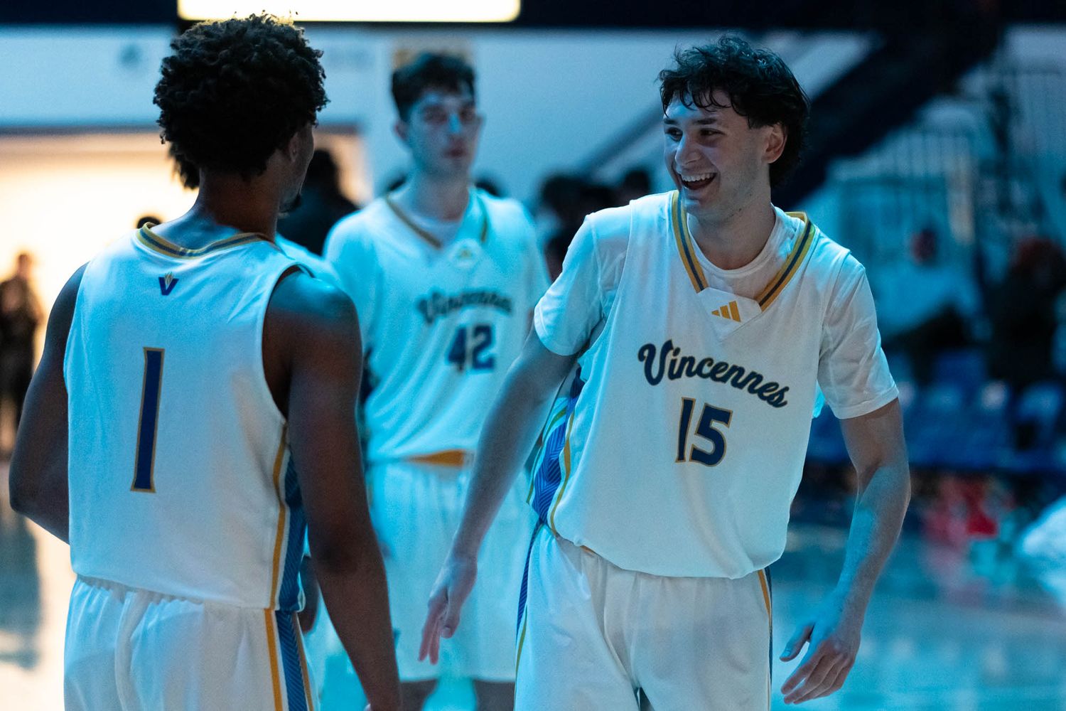 Vincennes basketball player number 15 smiling and celebrating with teammate number 1 during a game.