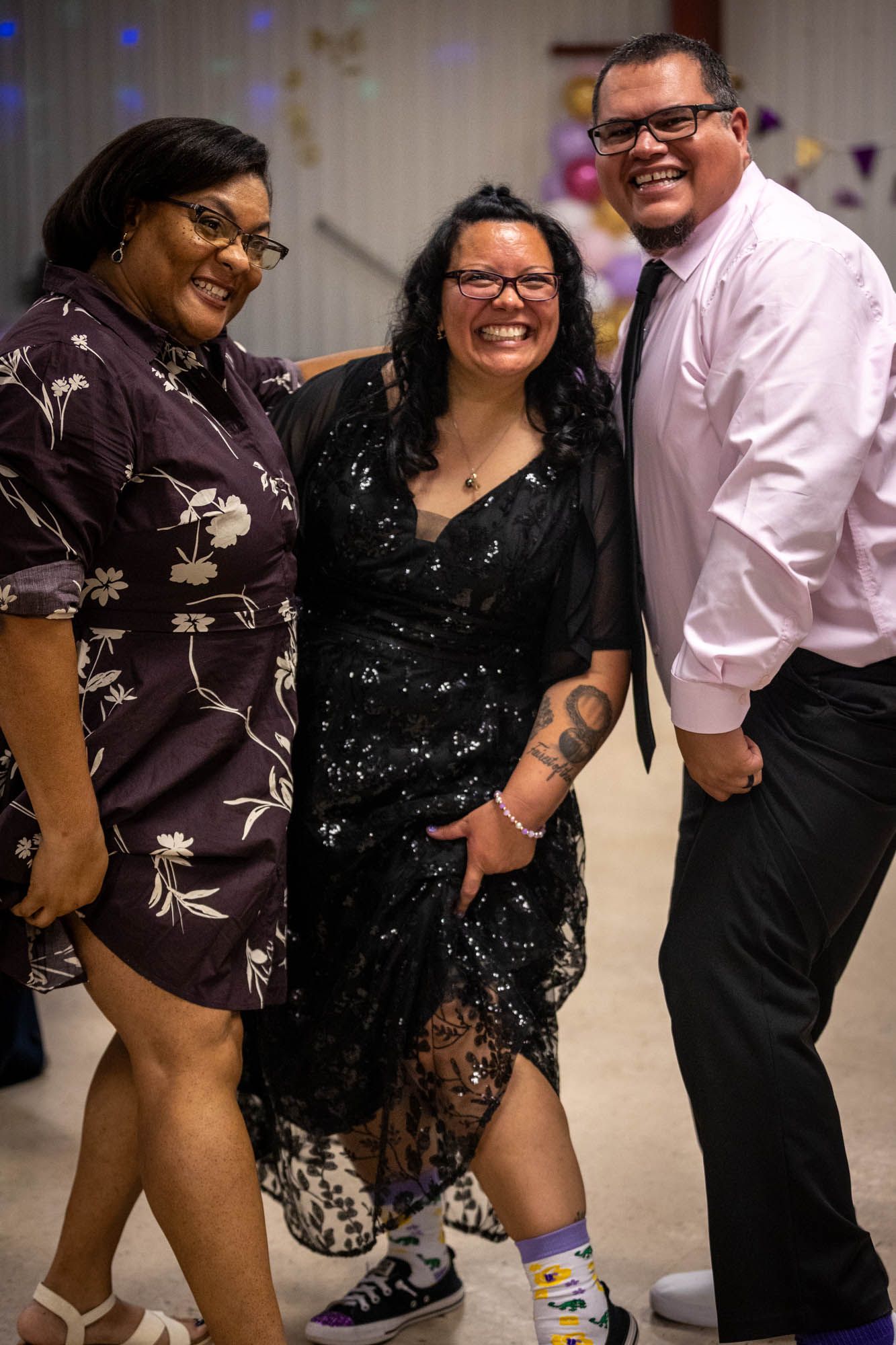 Three guests smiling and laughing together on the dance floor at a Quinceañera reception.