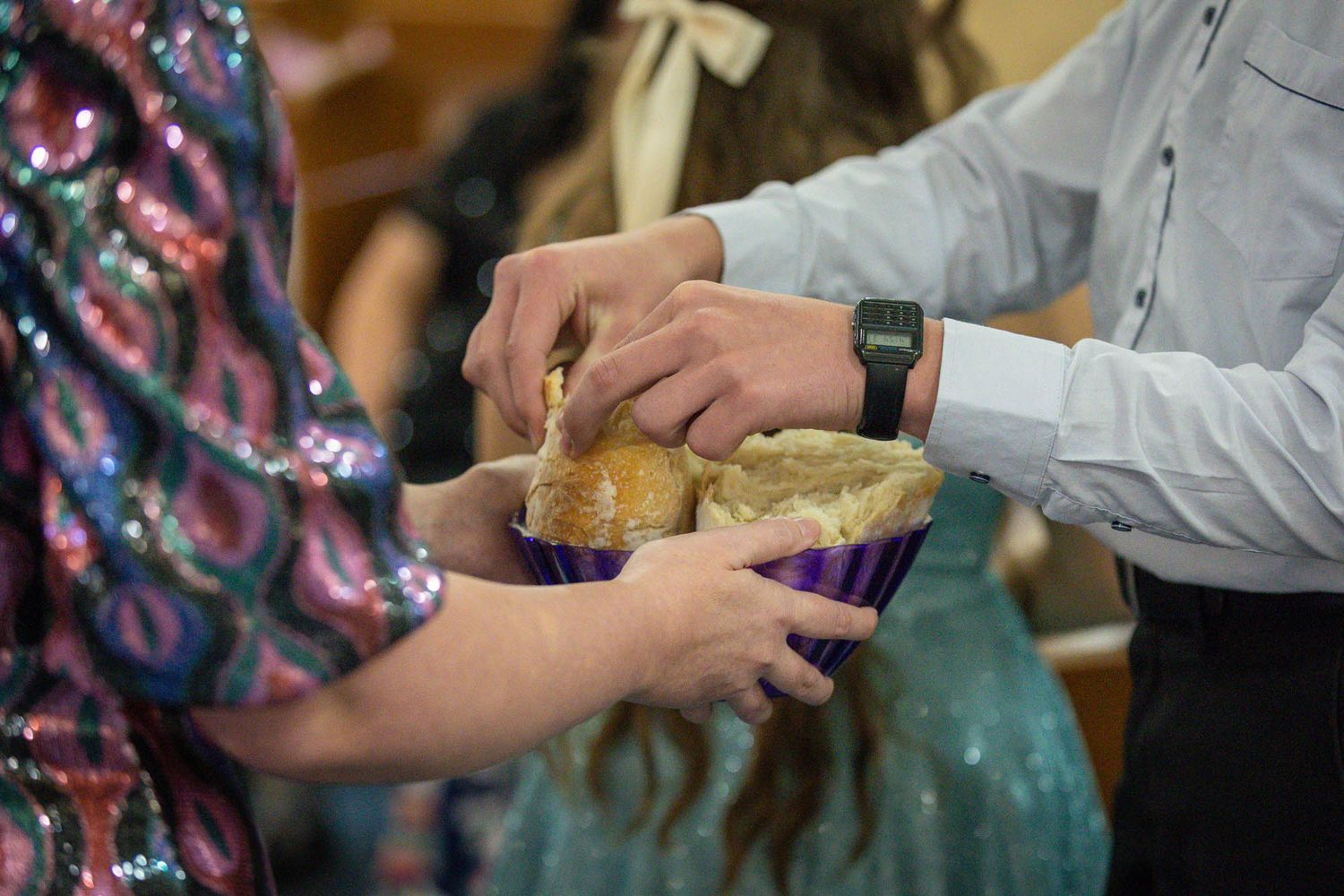 Guests reach into a basket of bread rolls during a quinceañera church ceremony.