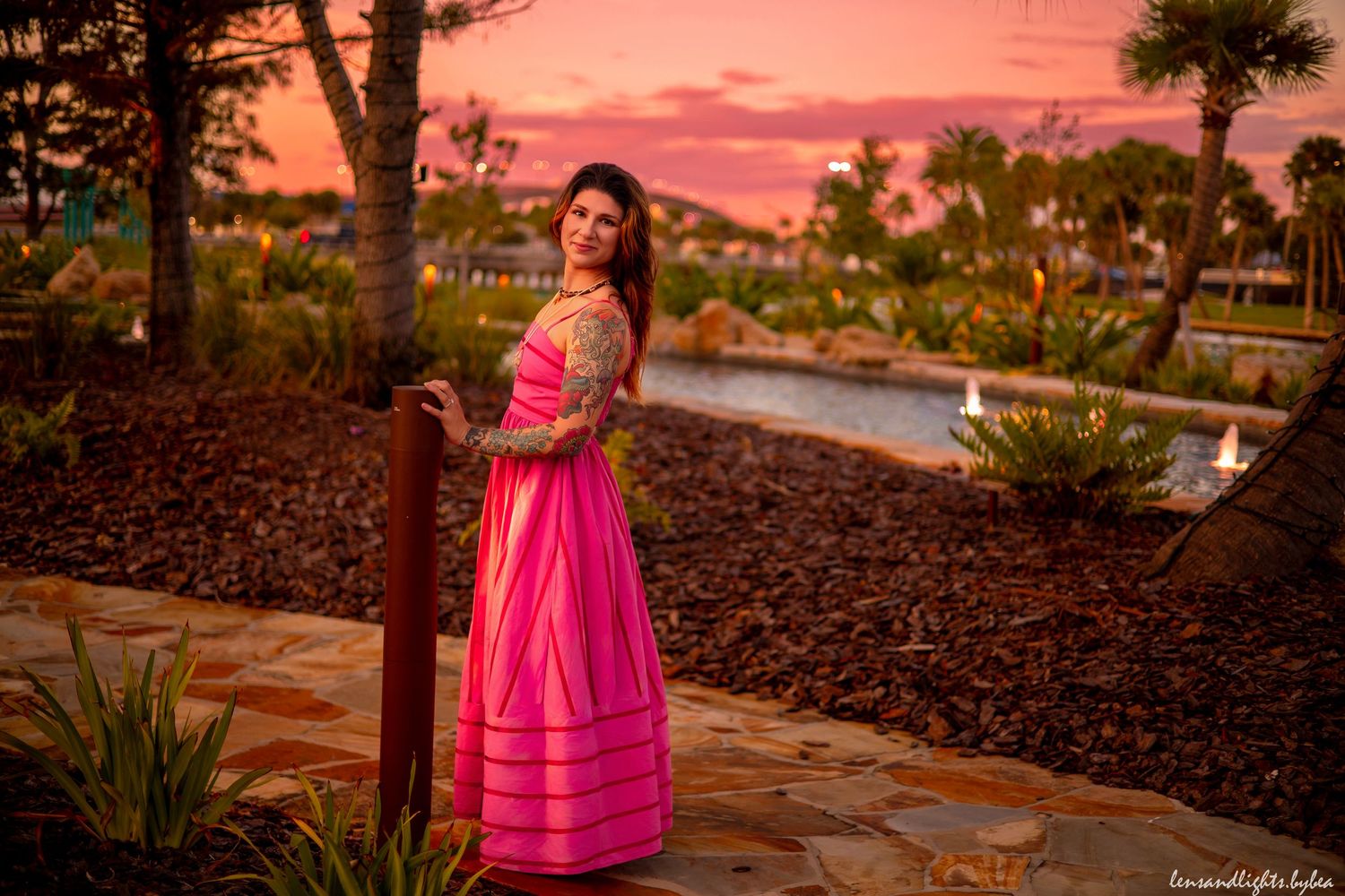 Romantic evening photoshoot in garden setting with pink sunset sky.