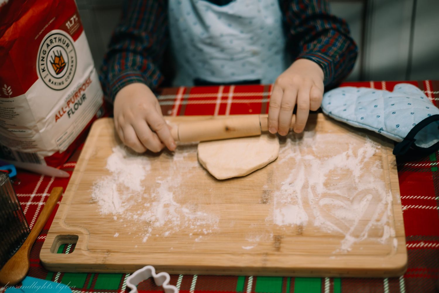 A sequence of hands rolling out dough on a wooden cutting board with flour scattered across the surface.