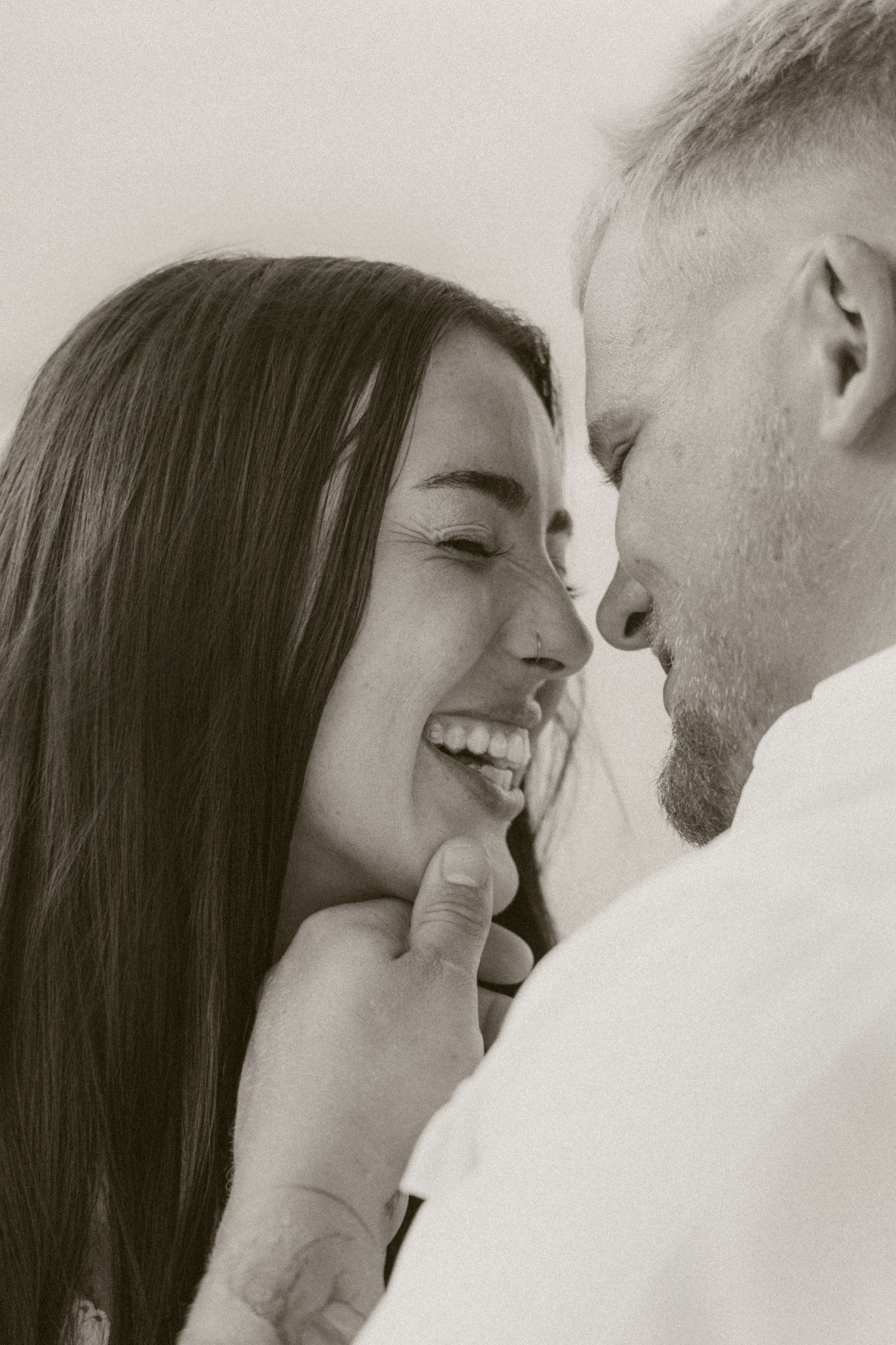 Black and white photo of a laughing couple sharing a tender, joyful moment.