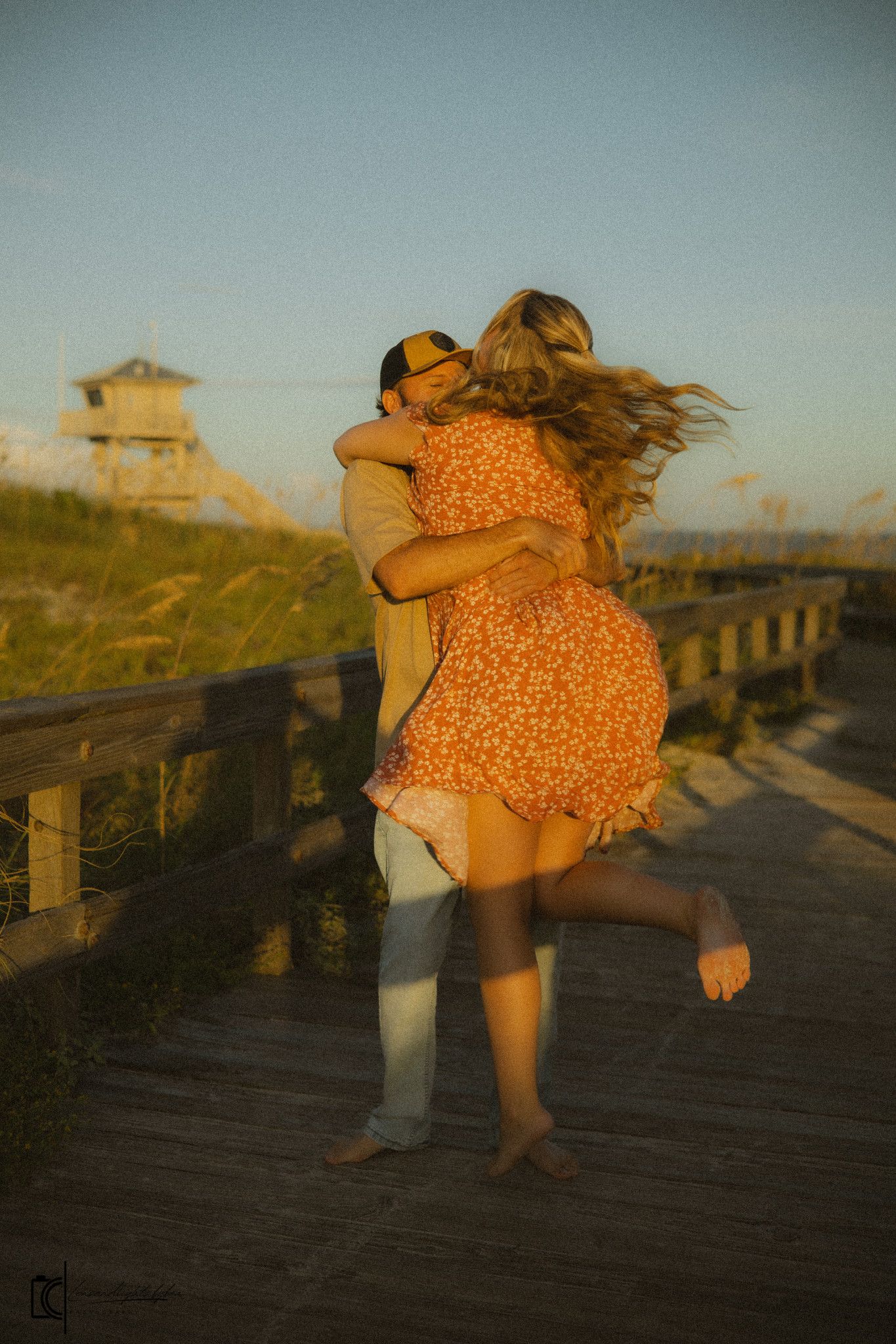 A couple dancing together on a wooden boardwalk at sunset, creating a romantic silhouette against the golden sky.