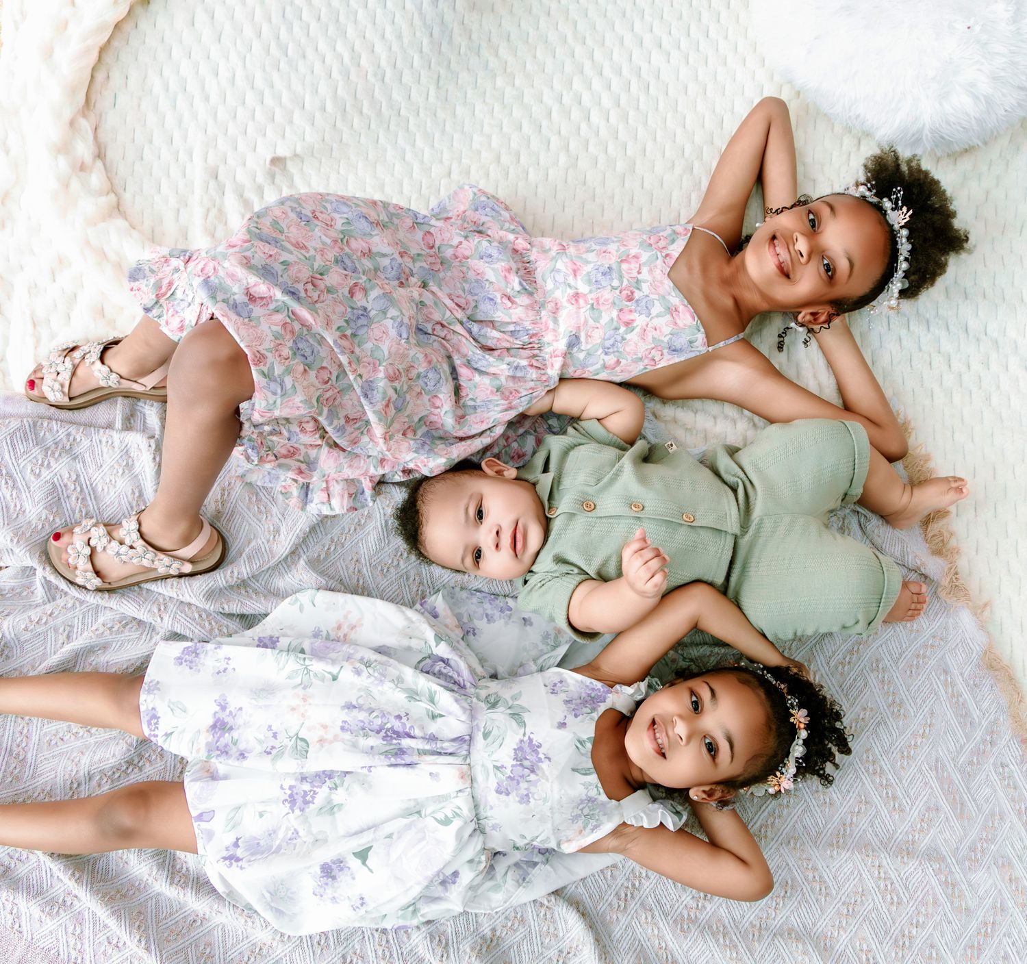 A series of candid photos showing a child in floral dress and green shirt laying on white bedding while playing and posing.