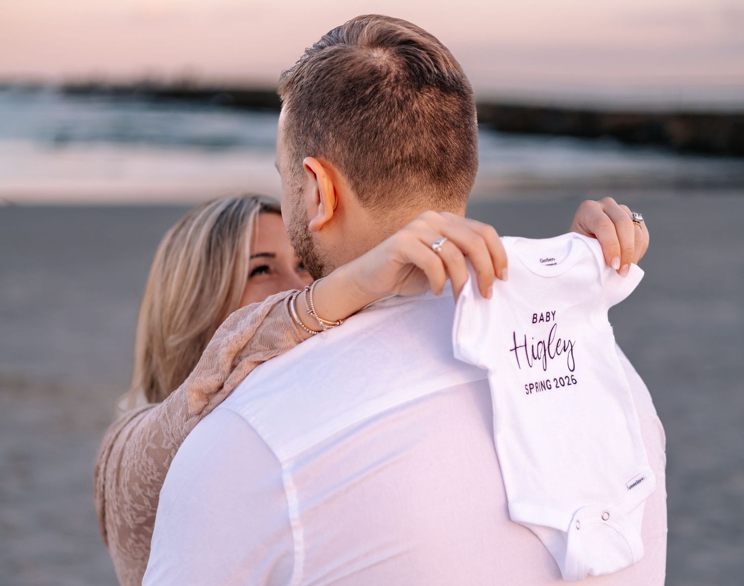 A couple in white outfits embraces on the beach during sunset in a series of romantic photos.