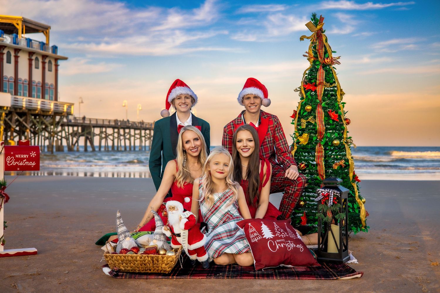 Holiday beach photos with decorated Christmas tree and Santa hats at sunset.