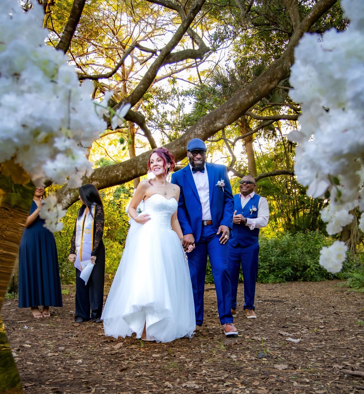 Couple in formal wedding attire shares playful moments under autumn trees during their outdoor photo session.