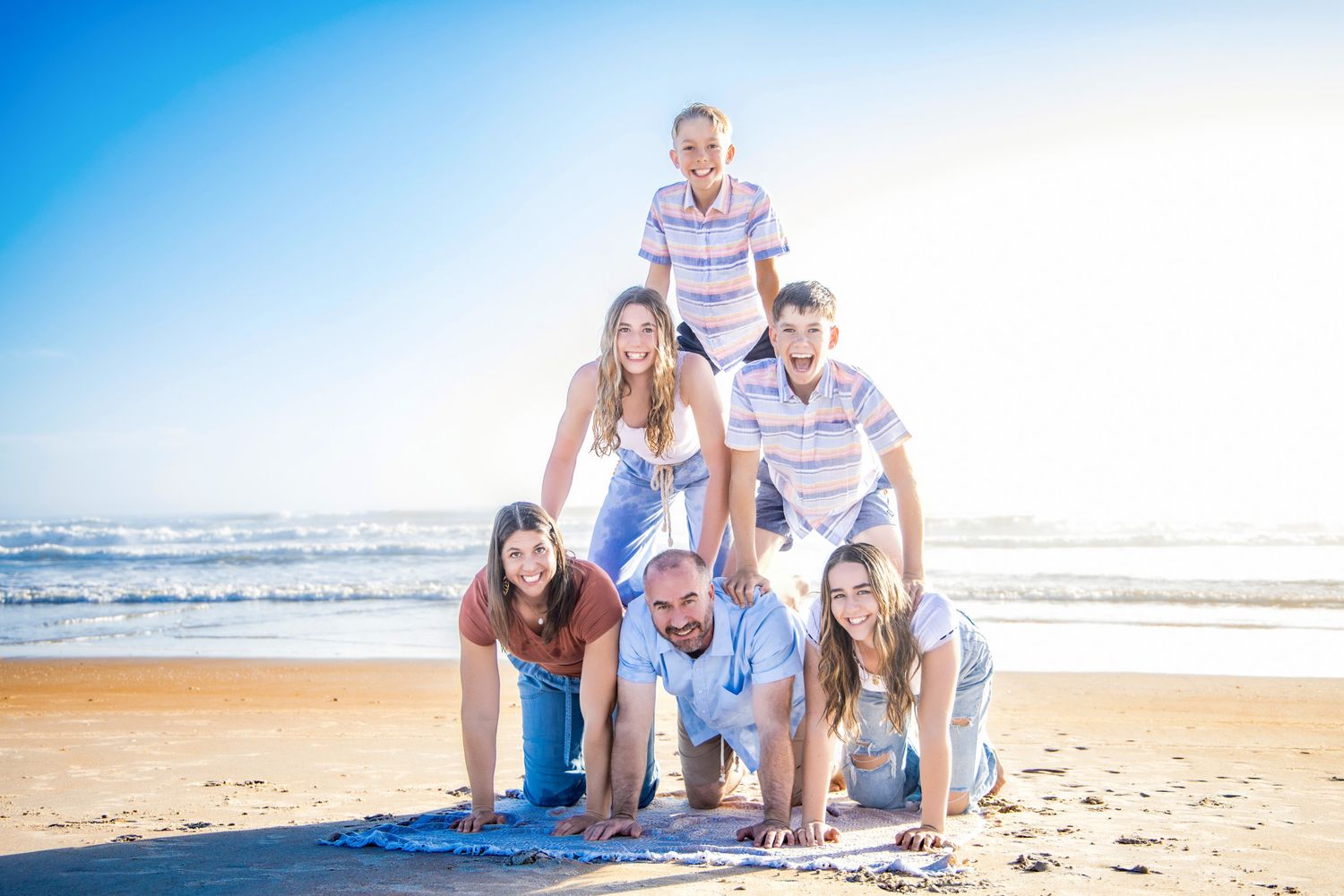 A group enjoys a relaxing afternoon together on a sunny beach with ocean waves in the background.