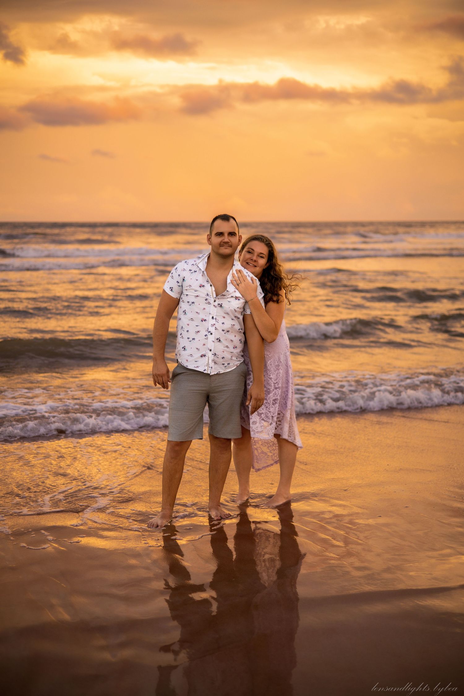 Family standing together on a beach during golden hour sunset.