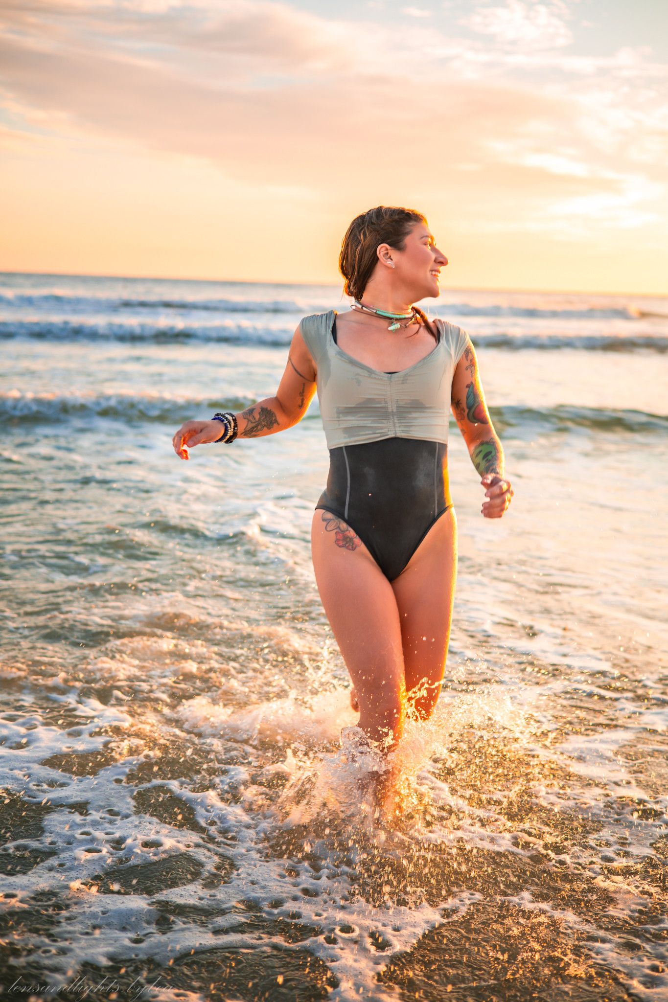 Person splashing through ocean waves at sunset creating golden reflections in the water.