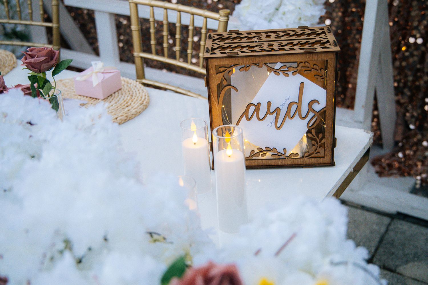 A rustic winter wedding reception table decorated with candles, greenery, and gold accents in a snowy setting.