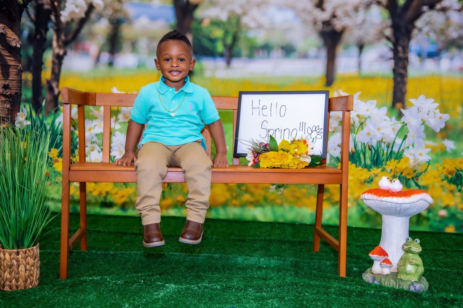 Spring photo session setup with wooden bench, cherry blossoms, artificial grass, and Easter decorations.