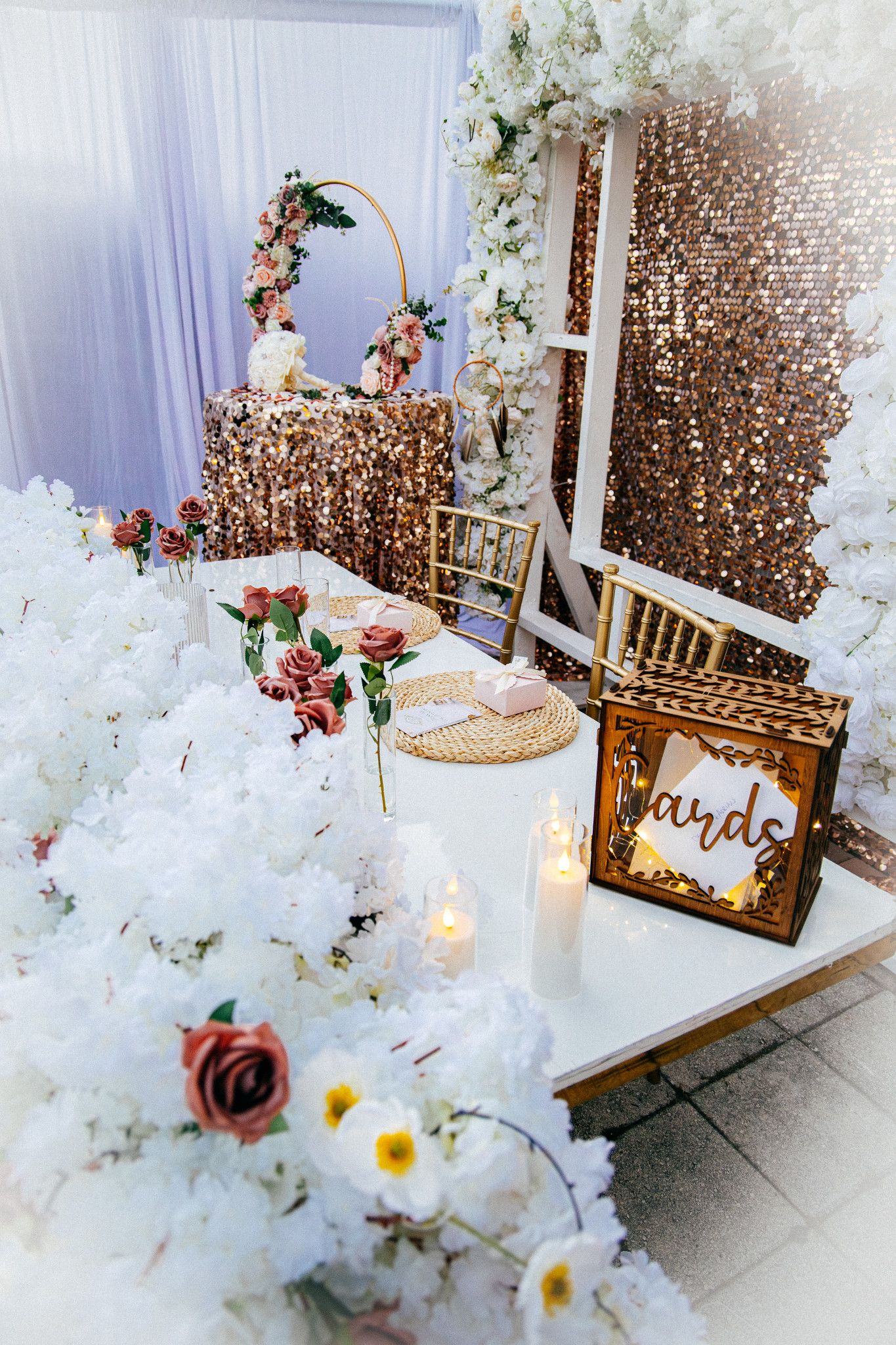 Elegant wedding decor featuring white floral arrangements, gold chairs, and shimmering confetti in a dreamy indoor setting.