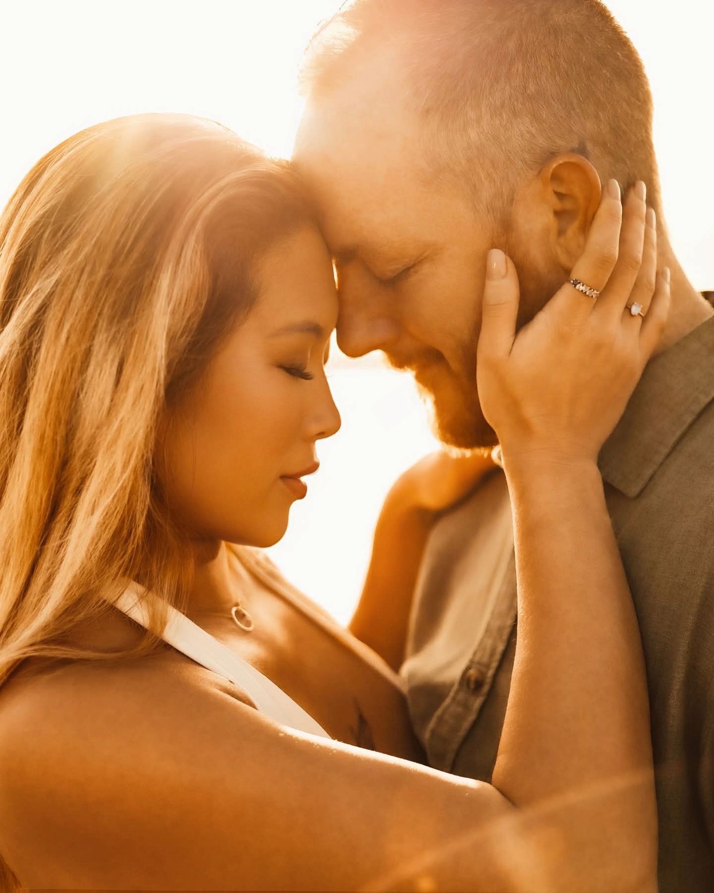 Romantic couple sharing an intimate moment at sunset with warm golden lighting.