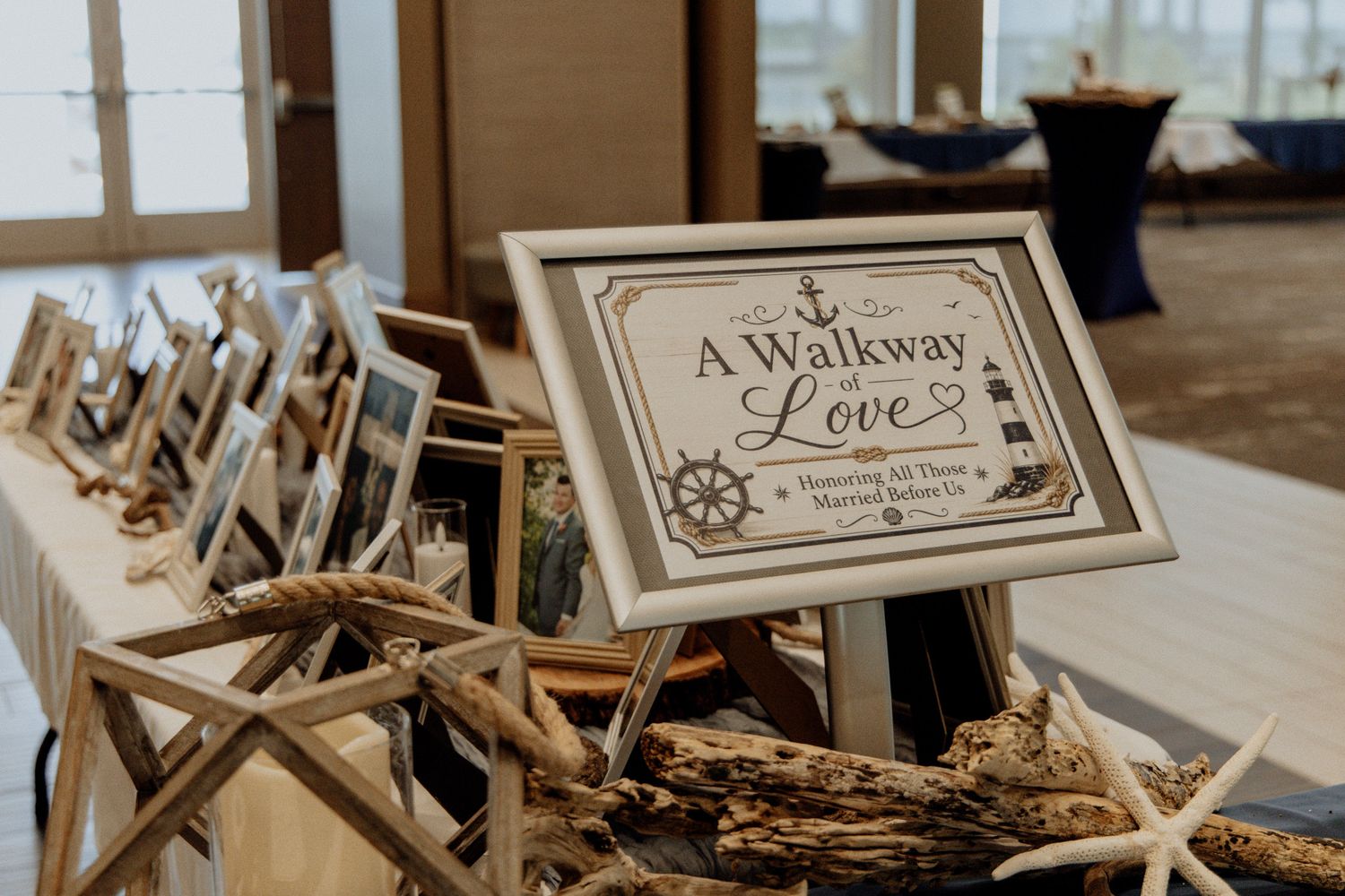 Nautical wedding walkway of love sign display with driftwood, starfish, and framed photos on a decorated table.