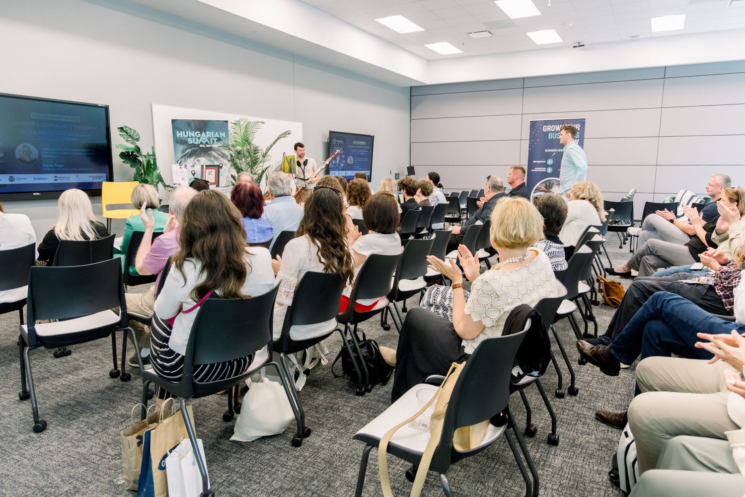 Audience members seated in rows at a professional conference presentation in a modern meeting room.