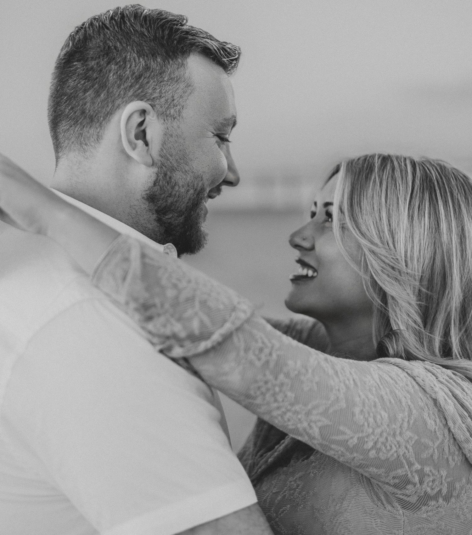 A romantic black and white photo series showing a couple embracing and laughing together in intimate moments.