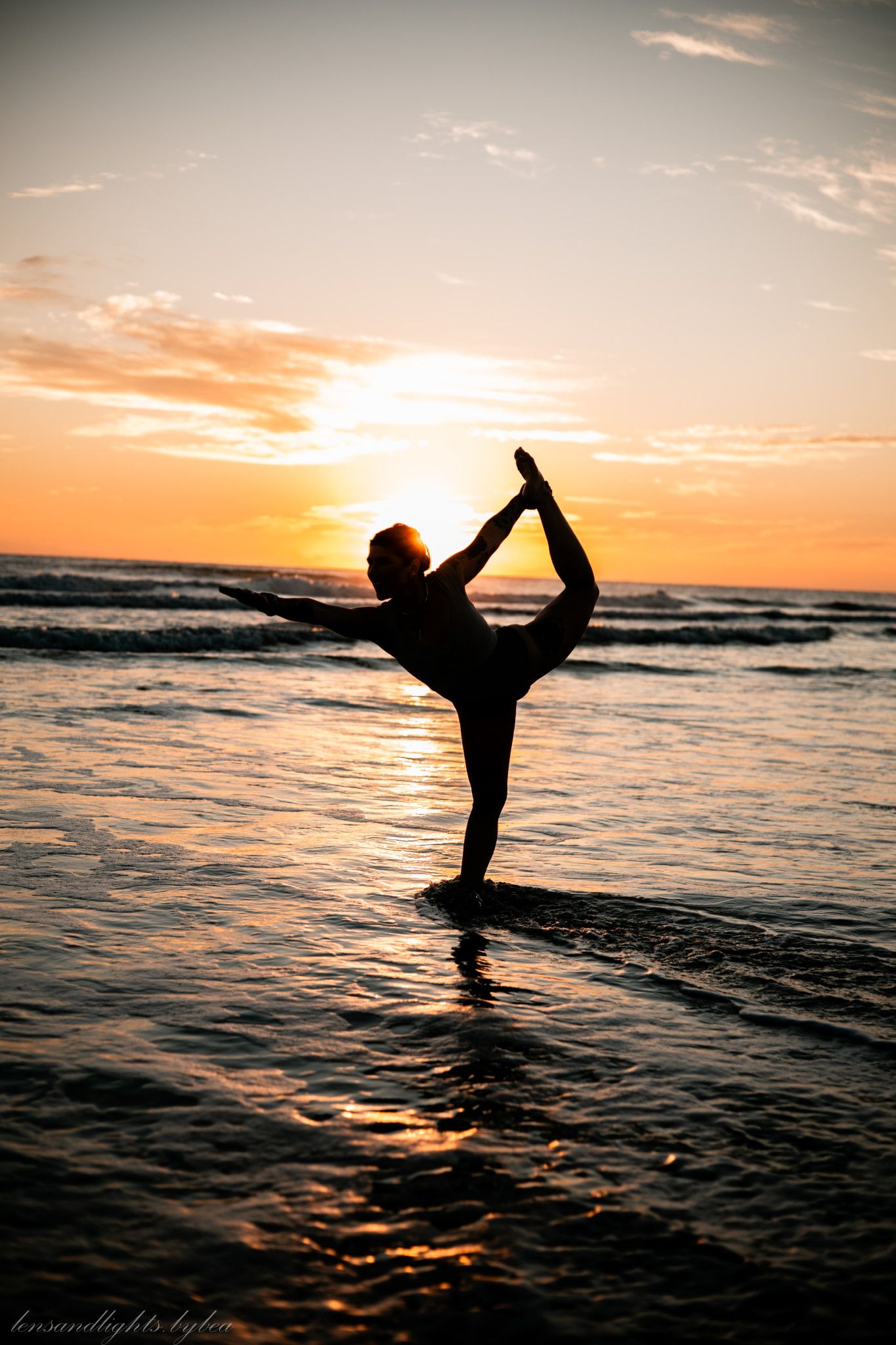 Silhouette of a person doing yoga poses against a dramatic beach sunset.